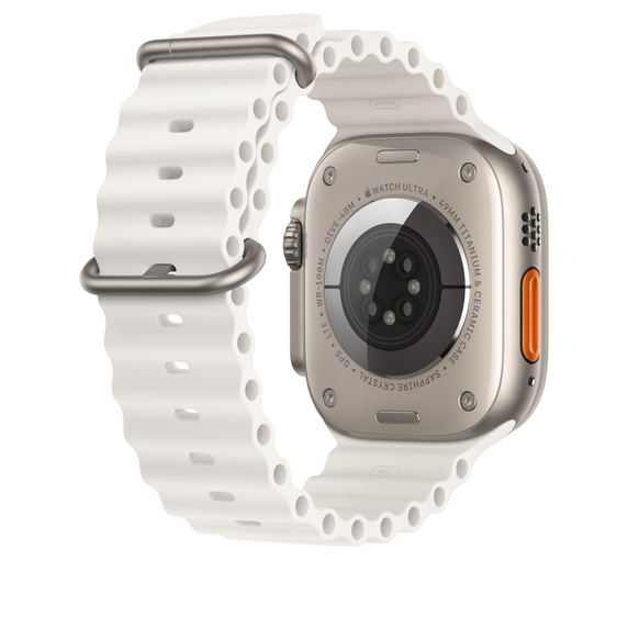 Apple Watch Ultra plateado con banda blanca. La parte trasera muestra sensores y etiquetas.