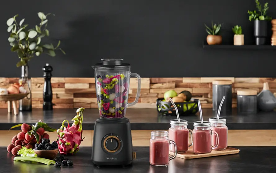 Blender with fresh ingredients and three smoothies.