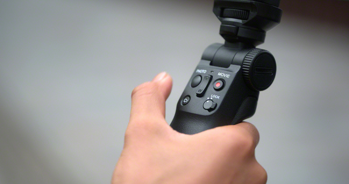 Eine Hand, die ein schwarzes Gimbal hält. Das Gimbal hat verschiedene Knöpfe und einen Griff.