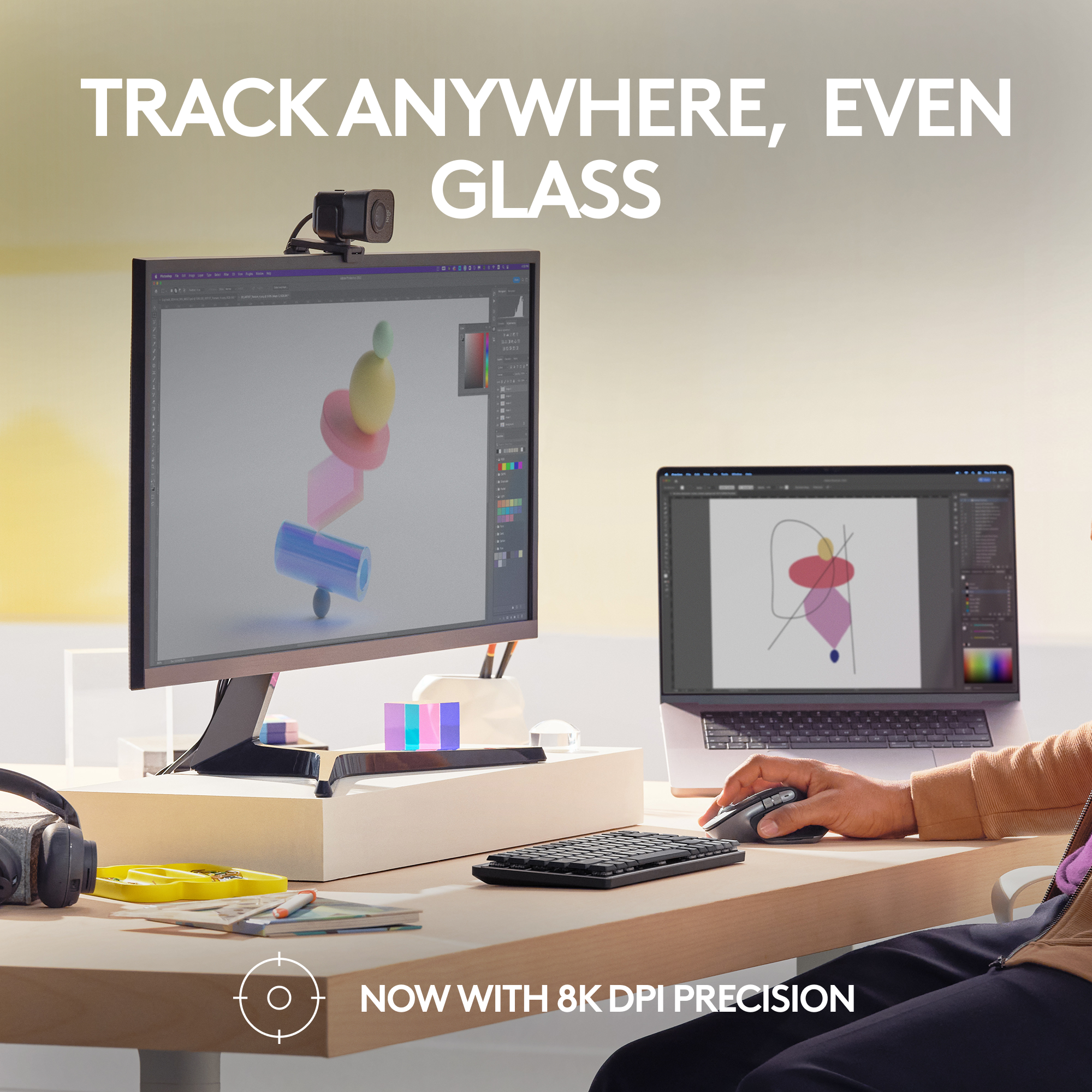 Eine Person benutzt Maus und Tastatur mit Monitor und Laptop auf einem Schreibtisch. Text: Track Anywhere, Even Glass.