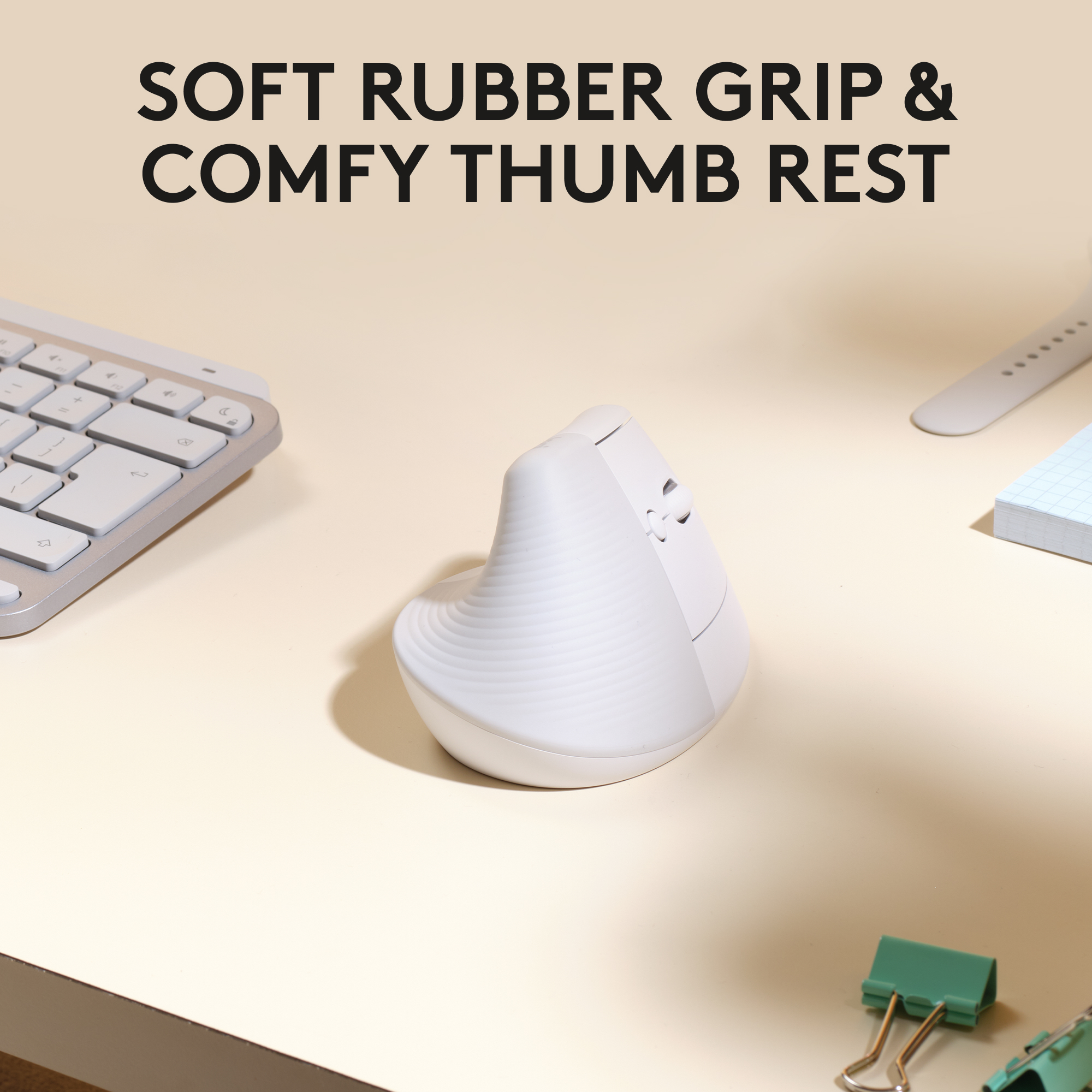 Weiße ergonomische Maus mit Daumenauflage auf beiger Oberfläche, mit Tastatur und Zubehör.