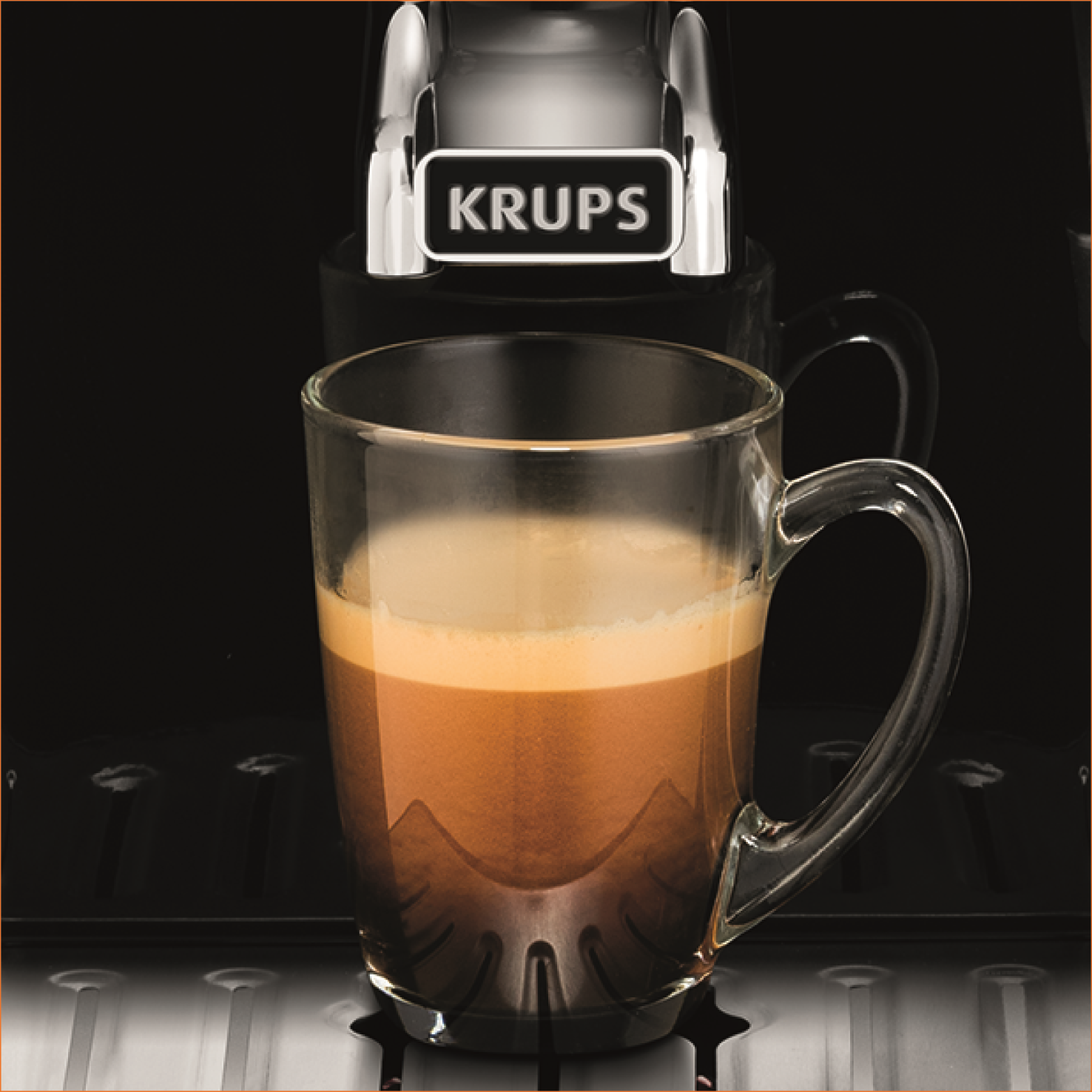 Una taza de vidrio con café siendo vertido por una cafetera Krups. La máquina es negra.