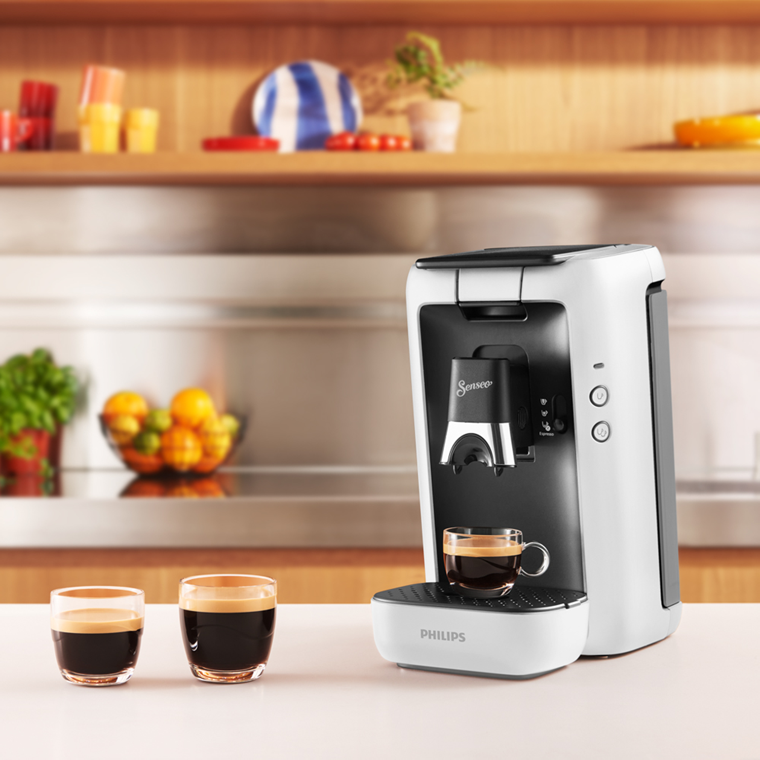 Een wit-zwarte koffiemachine met twee glazen koffie op het aanrecht. Er staat een dienblad onder.