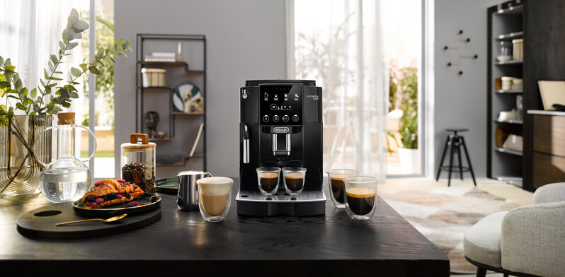 A black coffee machine with two espresso shots and a table setting.
