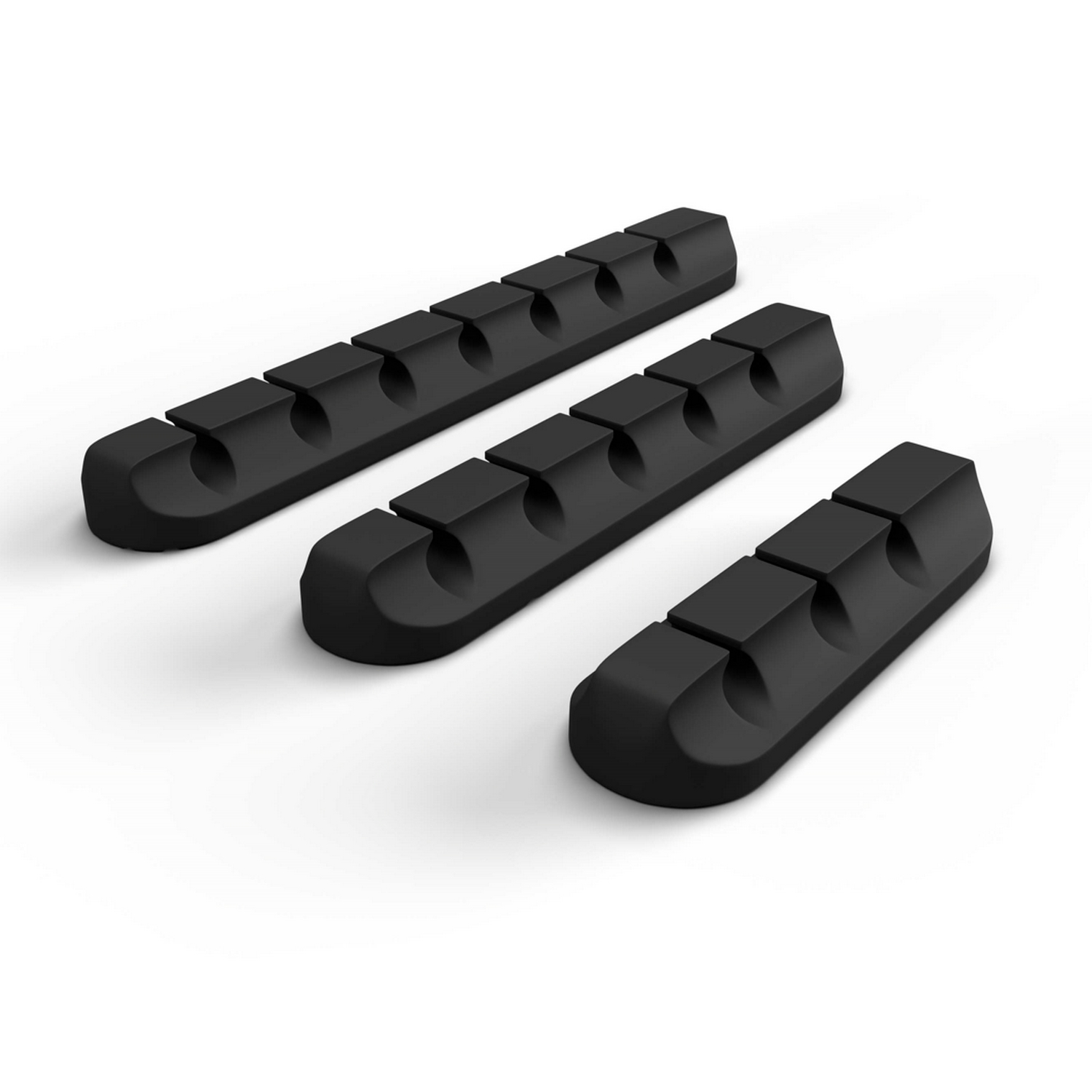 Tres organizadores de cables negros sobre una superficie blanca.