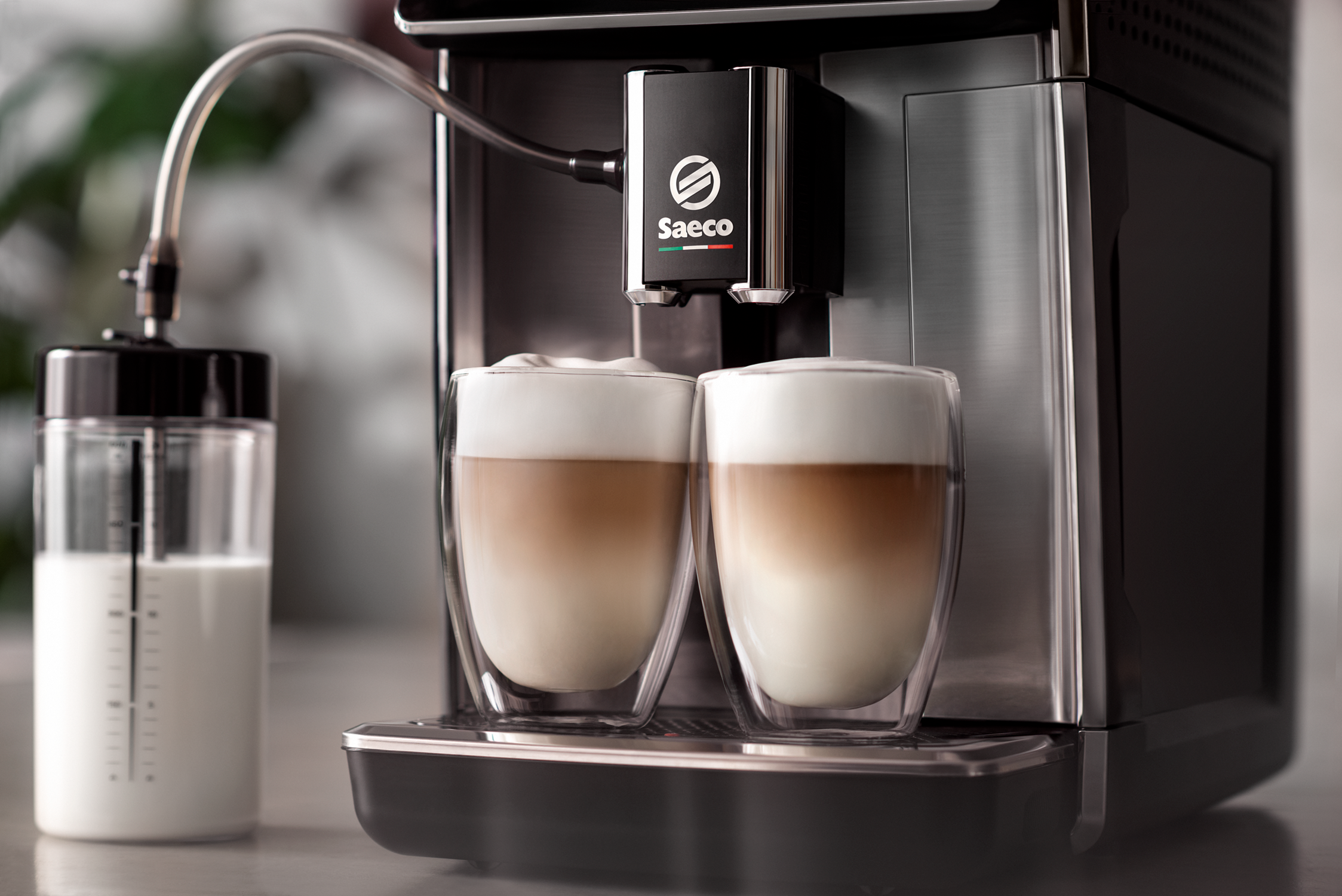 Espressomachine die koffie zet in twee glazen bekers, met een melkcontainer links.