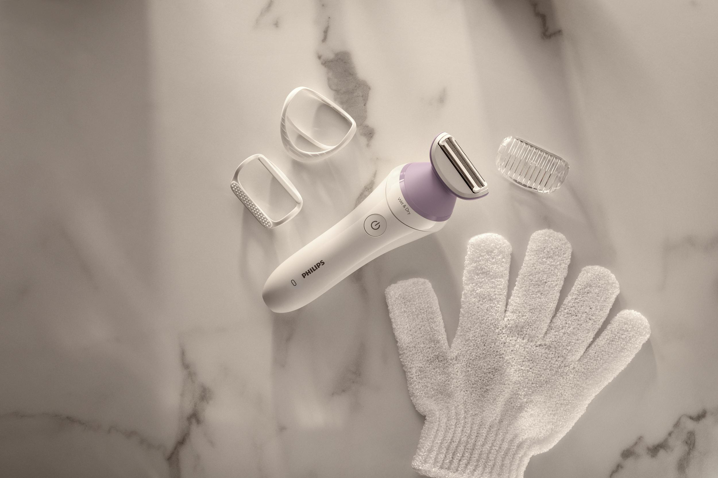 Ein elektrischer Rasierer mit Zubehör und einem weißen Waschlappen auf einer Marmoroberfläche.