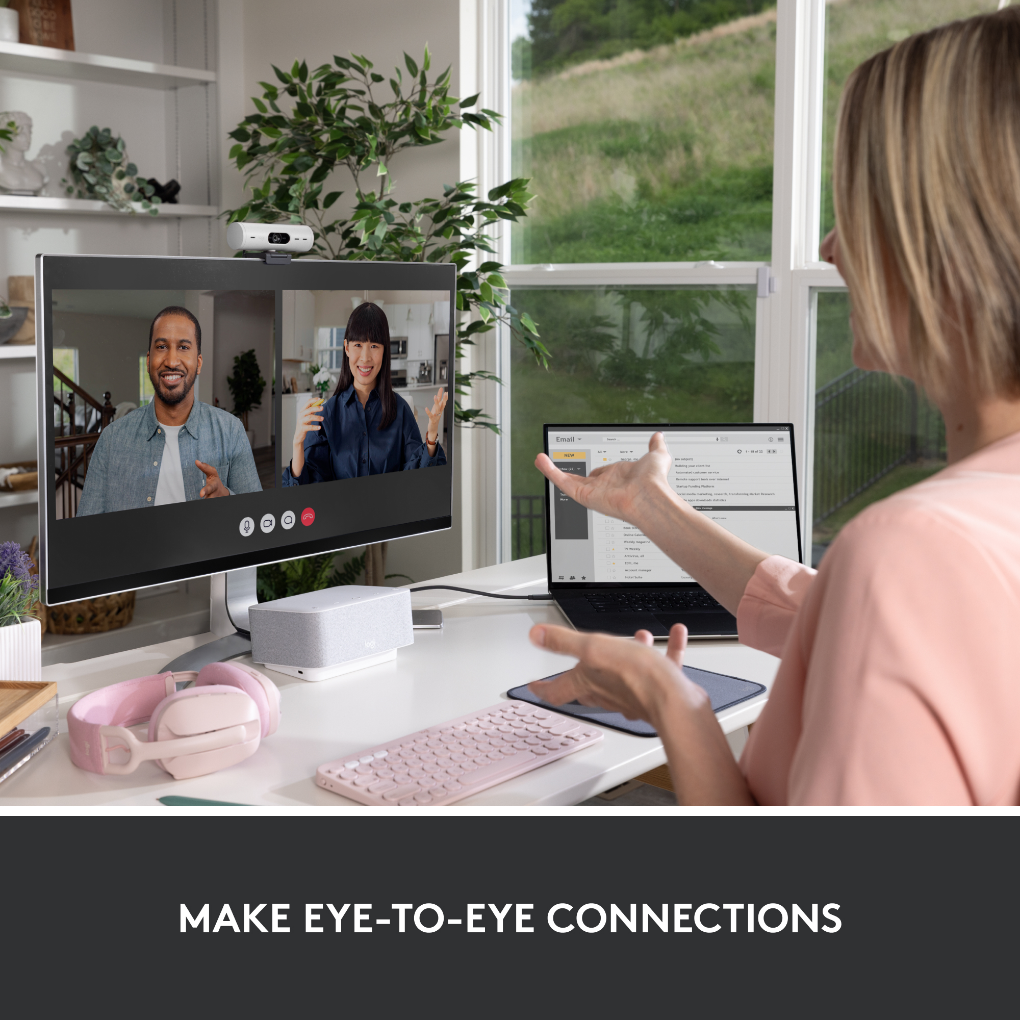 Une femme en appel vidéo avec deux personnes. Ordinateur portable et moniteur sur le bureau.