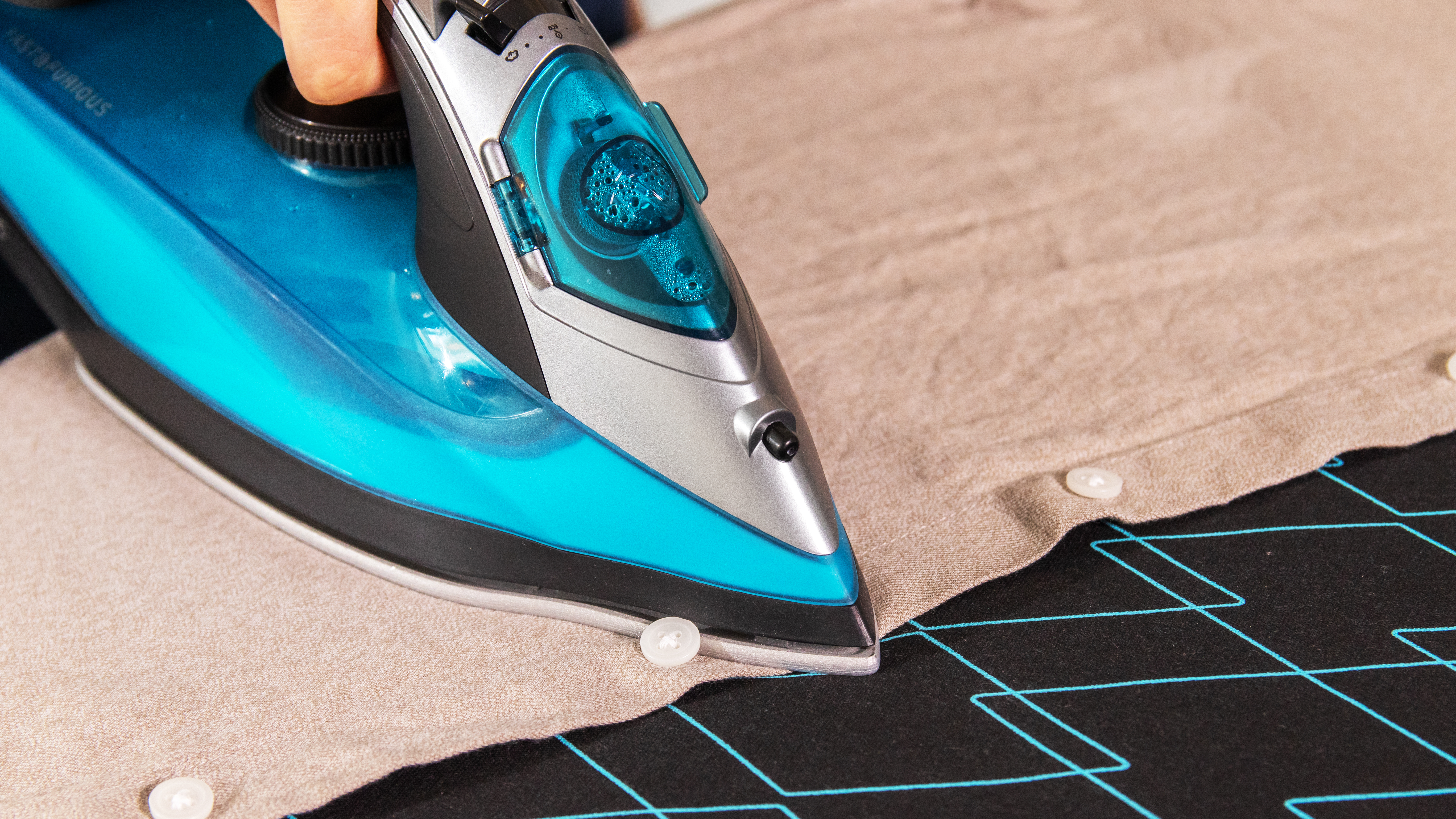 Planchando ropa en una tabla de planchar. Una persona está planchando una camisa. La tabla es negra.