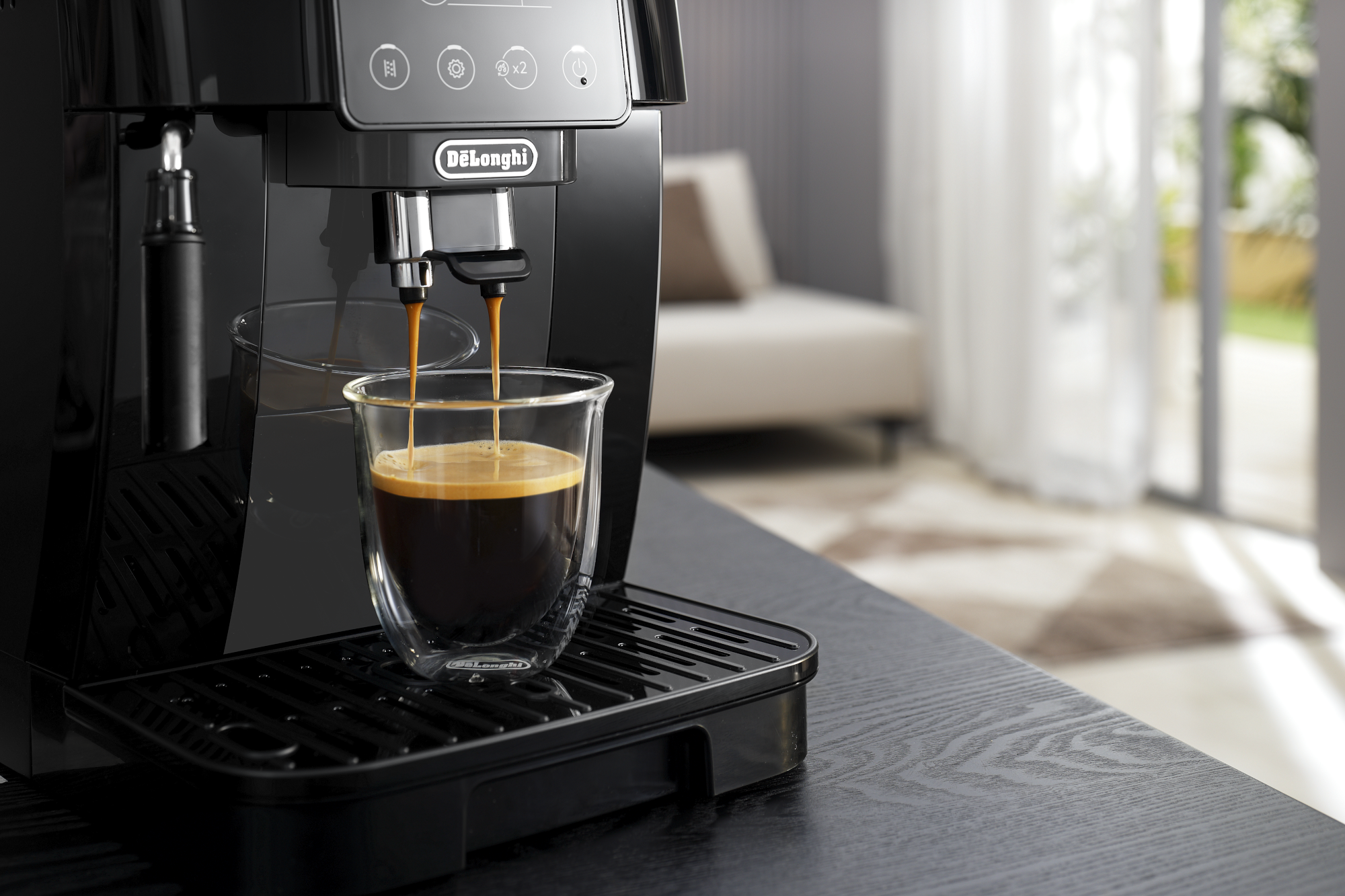 Une machine à expresso De'Longhi noire avec du café versé dans une tasse en verre.