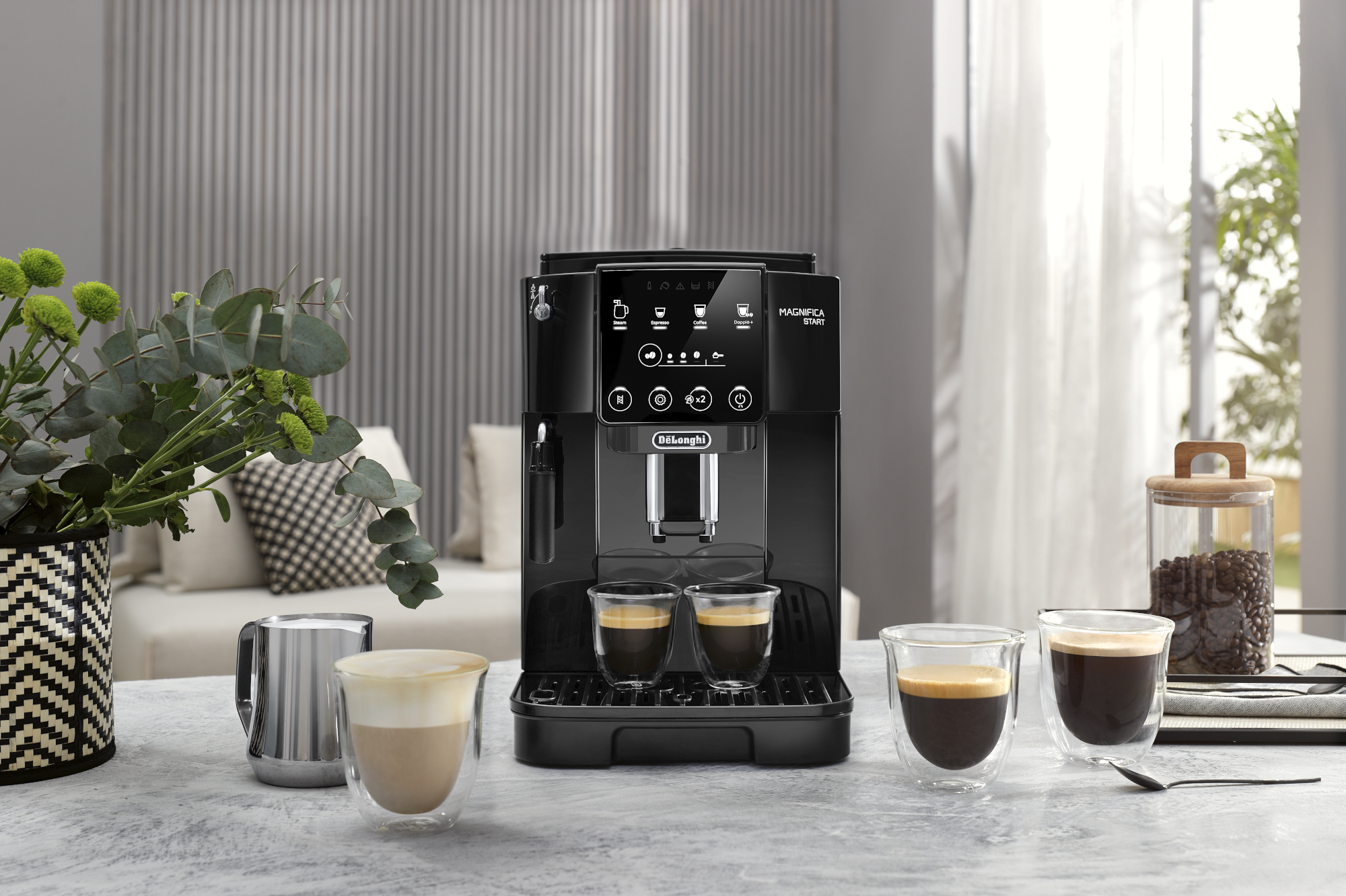 Une machine à café DeLonghi noire avec deux tasses d'espresso. Il y a aussi des verres à latte.