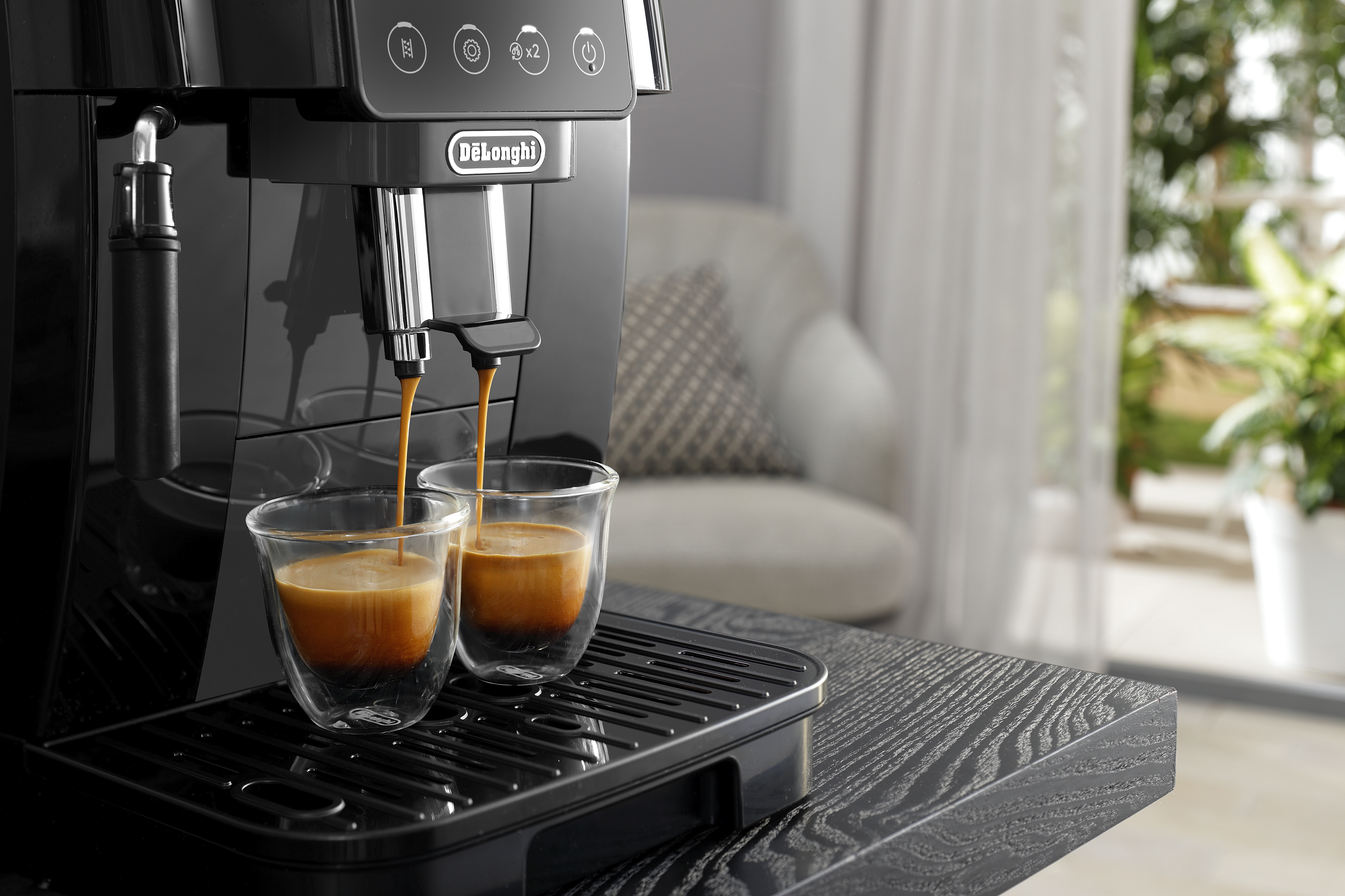 Machine à expresso distribuant de l'expresso dans deux tasses en verre, gros plan.