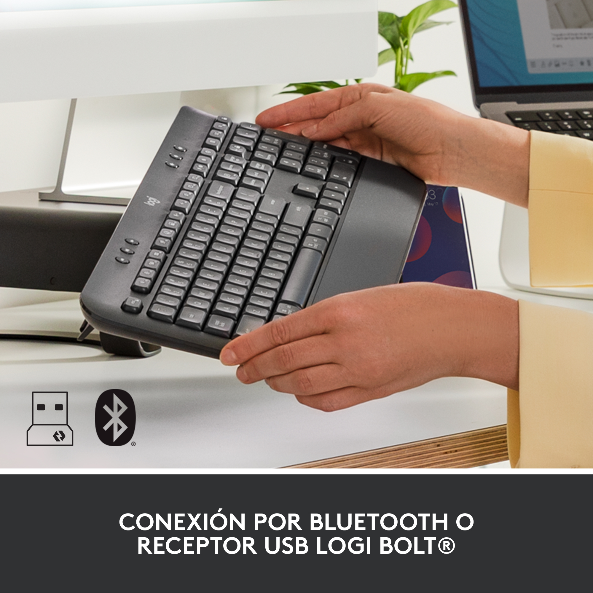 Manos de una persona sosteniendo un teclado negro con un símbolo USB y Bluetooth.