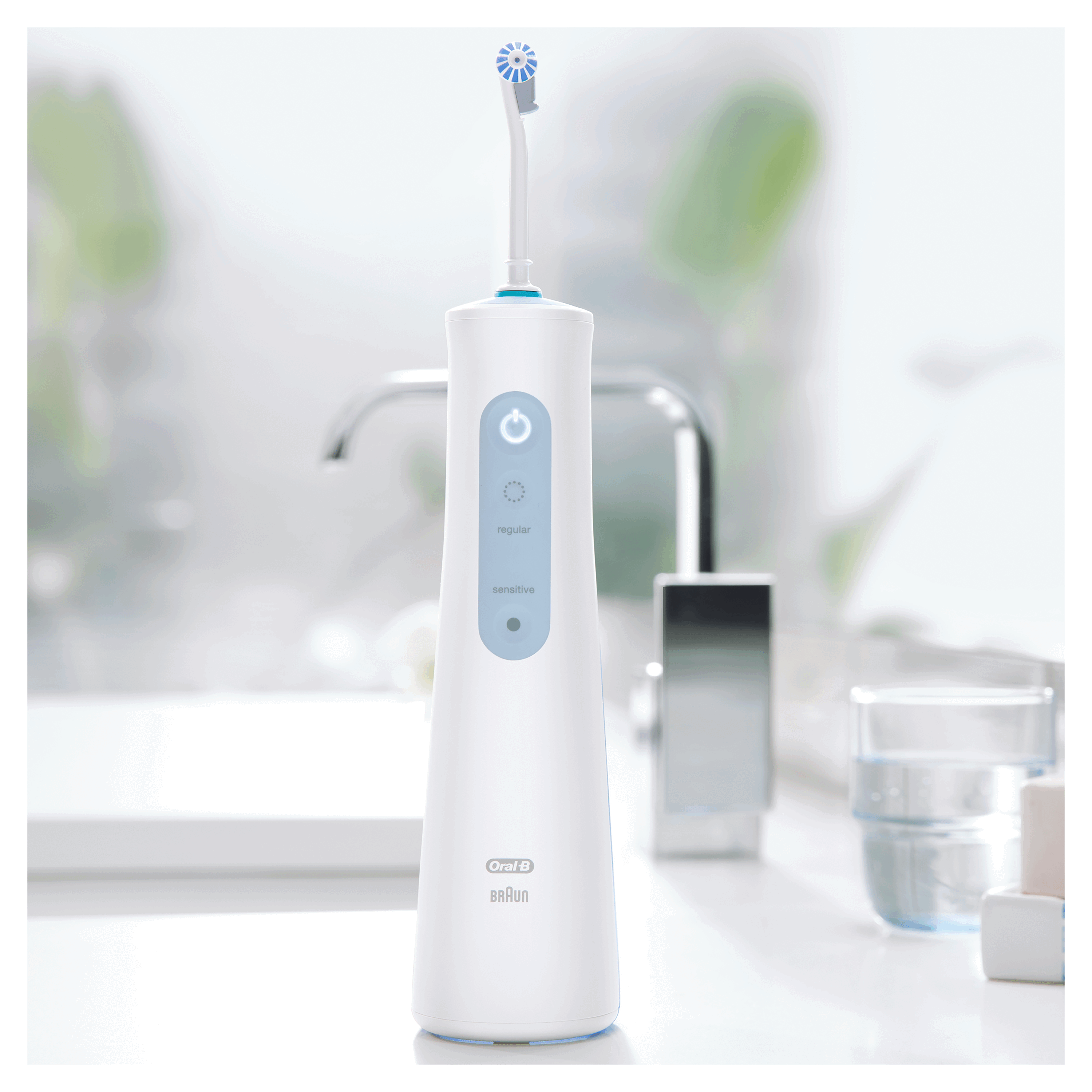 Witte waterflosser met een blauwe knop, een witte achtergrond en een wastafel op de achtergrond.