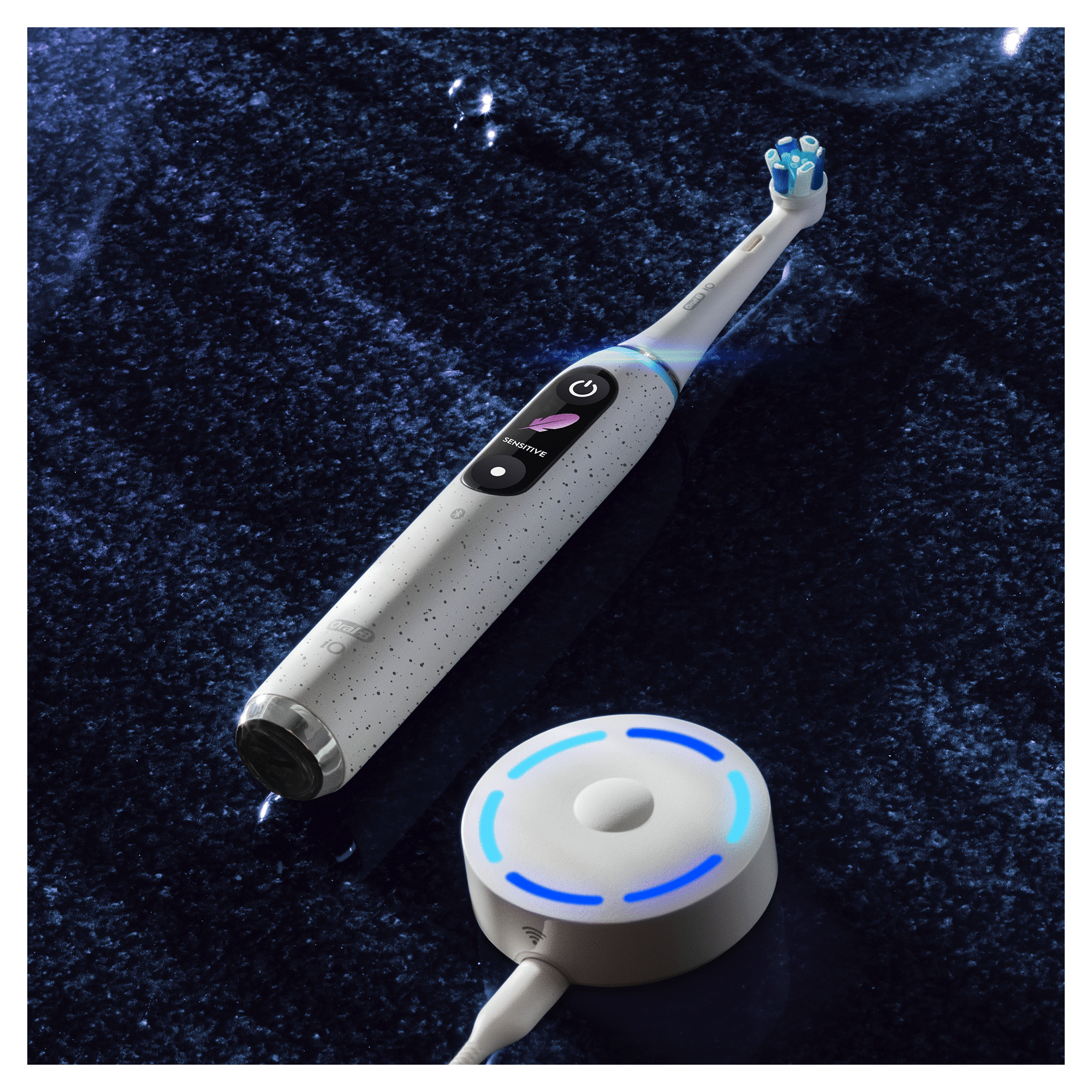 White electric toothbrush with a charging base, on a blue surface.