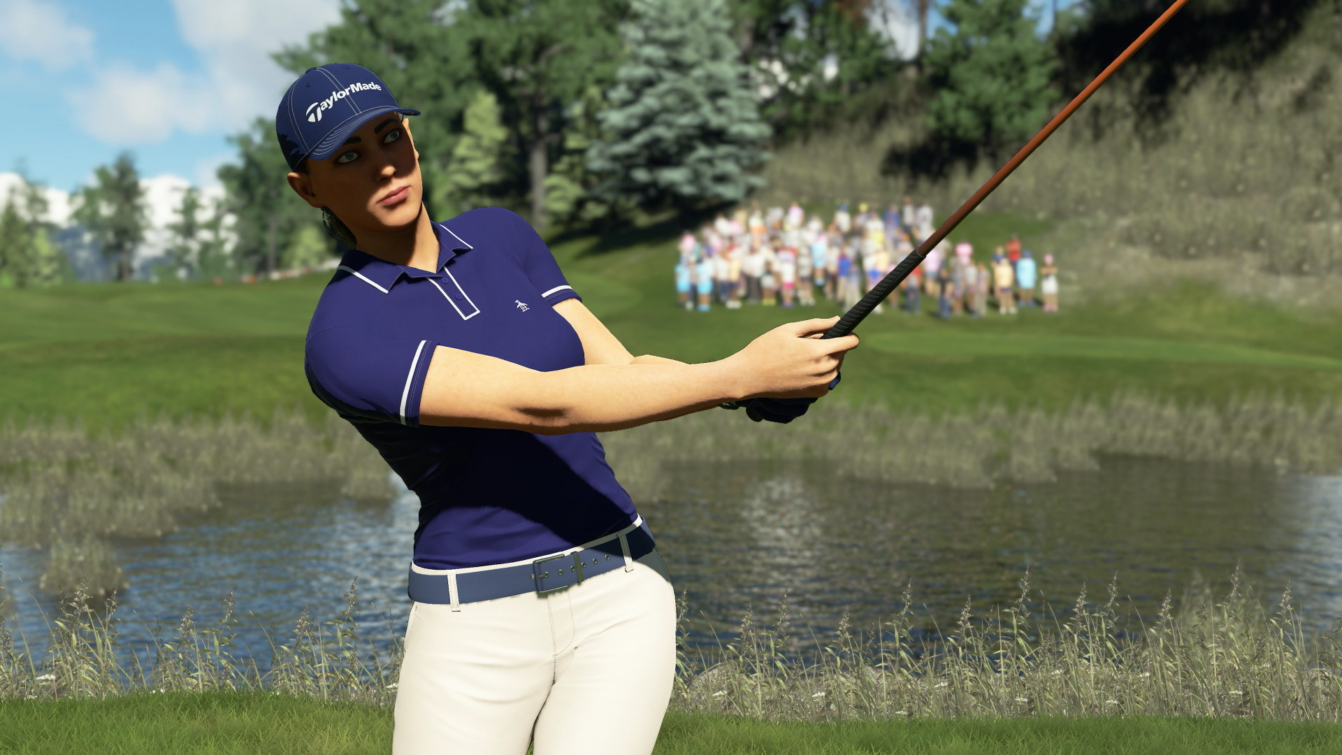 Una donna in abbigliamento da golf swing un bastone da golf su un campo, con uno stagno e una folla sullo sfondo.