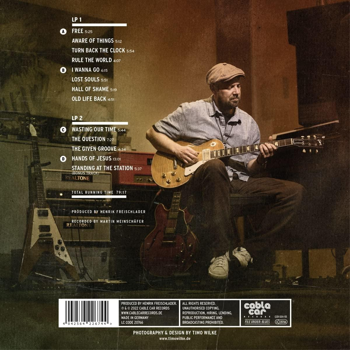 Albumcover mit einem Mann, der Gitarre spielt. Im Hintergrund sind zwei weitere Gitarren zu sehen. Text listet Songtitel auf.