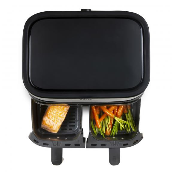 An open air fryer with two compartments containing salmon and carrots.