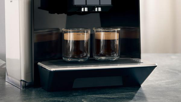 Zwei Glasbecher Espresso auf einer schwarzen Maschine. Eine Kaffeemaschine auf einer grauen Arbeitsplatte.