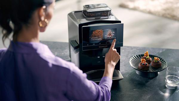 Frau, die eine Kaffeemaschine mit Touchscreen-Oberfläche benutzt.