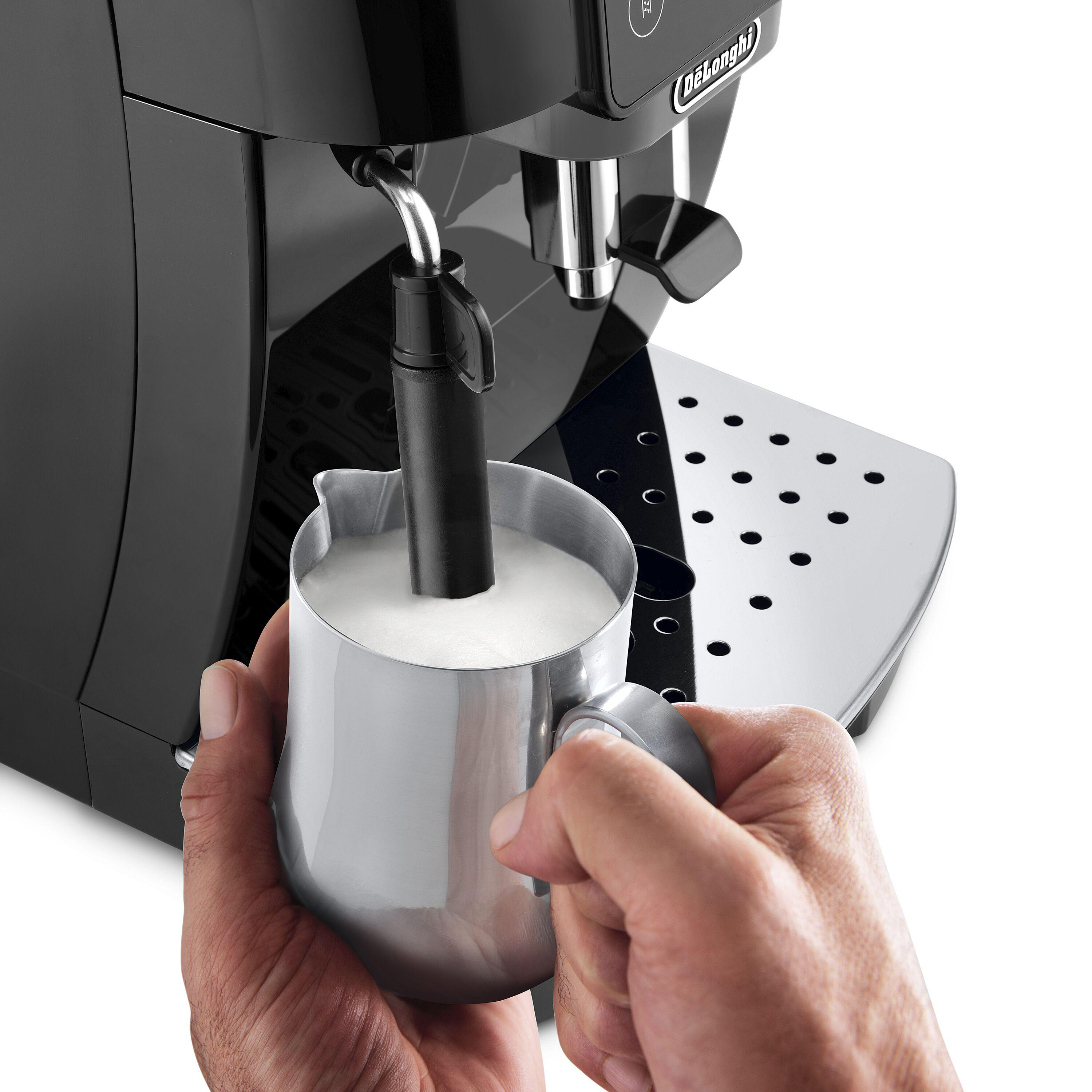 Hände einer Person, die einen Metallkrug halten und Milch mit einer De'Longhi Kaffeemaschine aufschäumen.