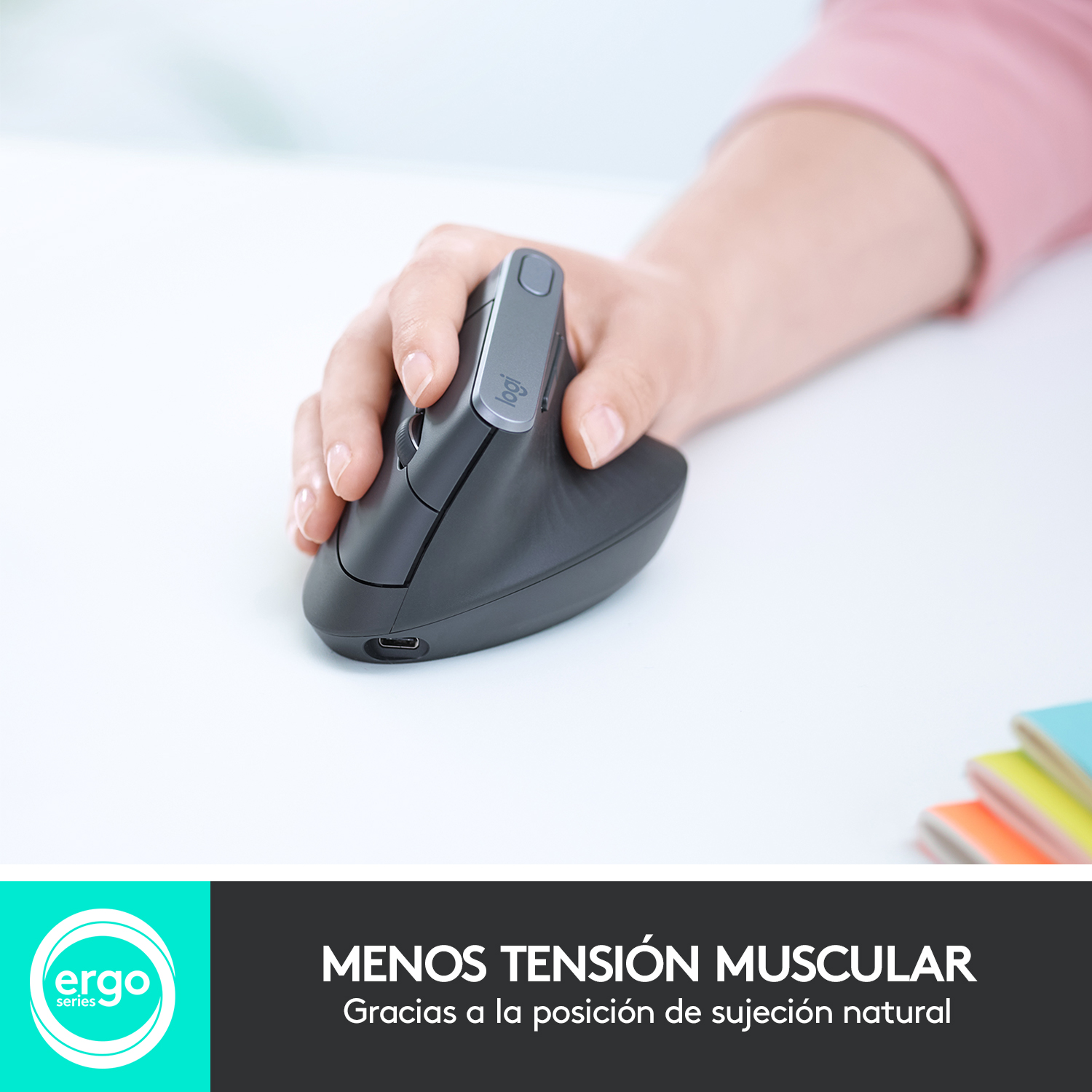 Una mano usando un ratón ergonómico gris. El texto 'MENOS TENSIÓN MUSCULAR' está debajo.