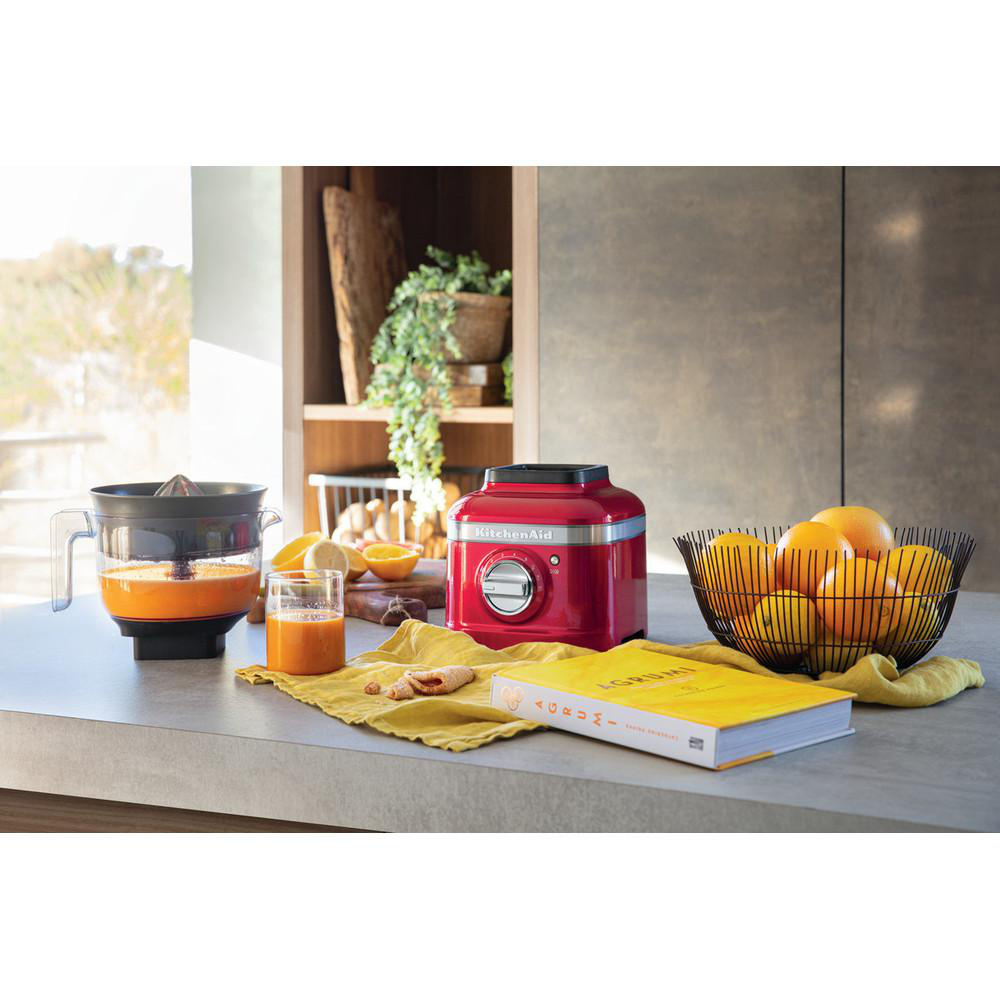 Eine Küchenszene mit Entsafter, Obst und einem roten KitchenAid-Mixer.