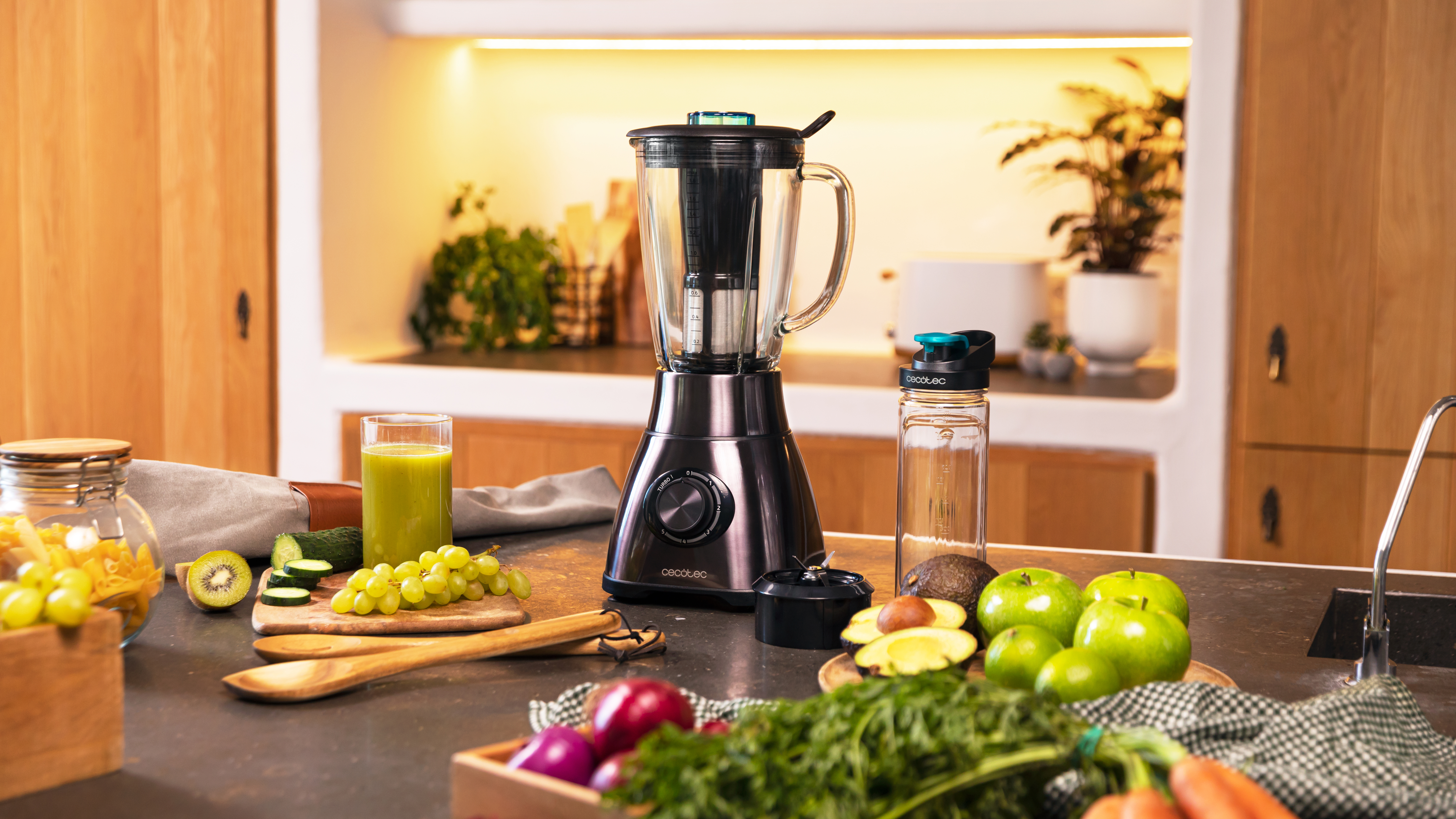 Una escena de cocina con una licuadora e ingredientes como frutas y verduras en una encimera.