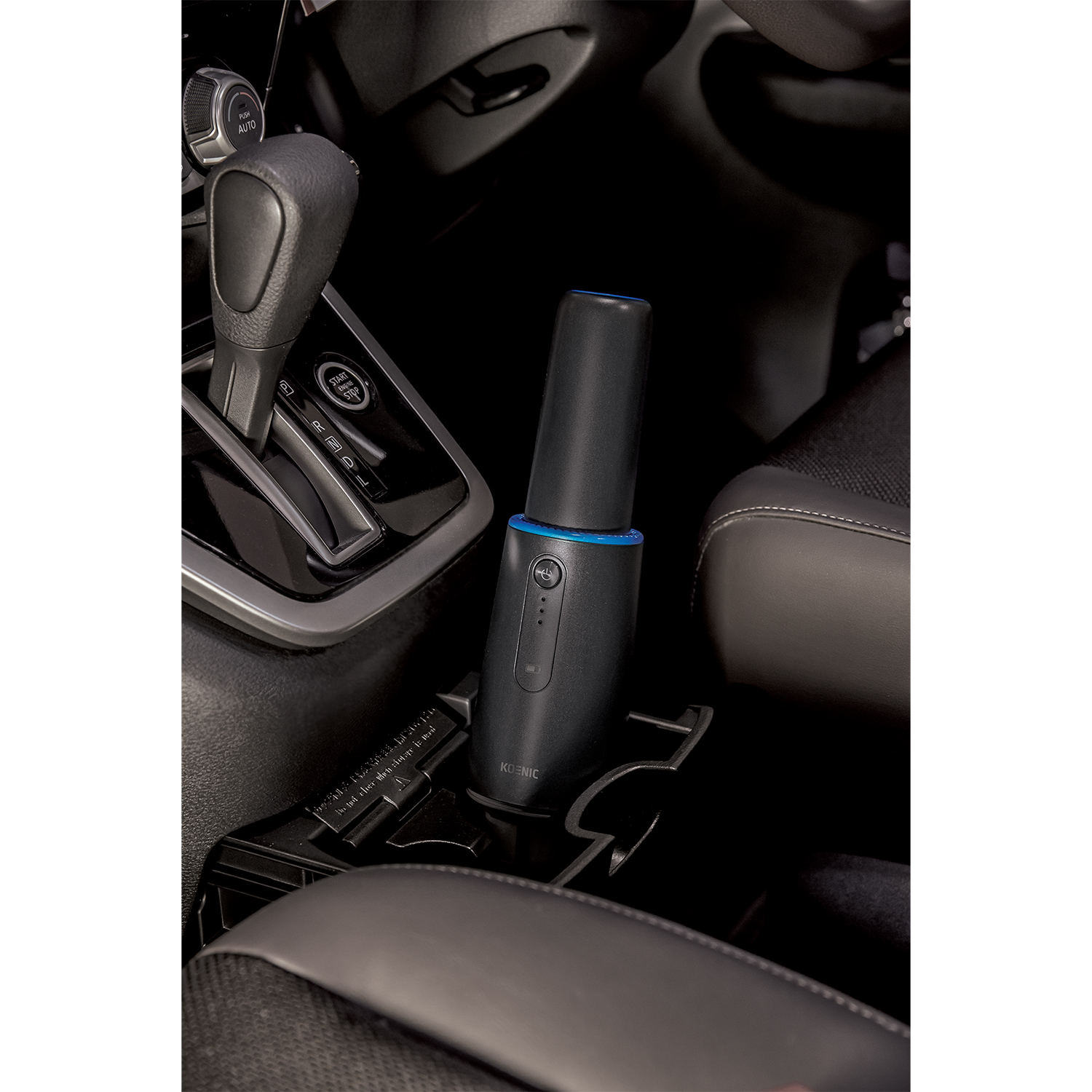 Un purificatore d'aria per auto nero in un portabicchieri per auto. Il purificatore è cilindrico con una luce blu.