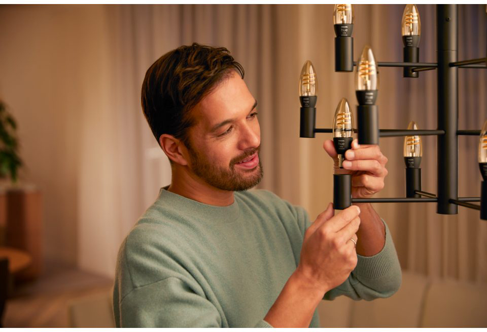 A man is installing a light bulb in a chandelier.