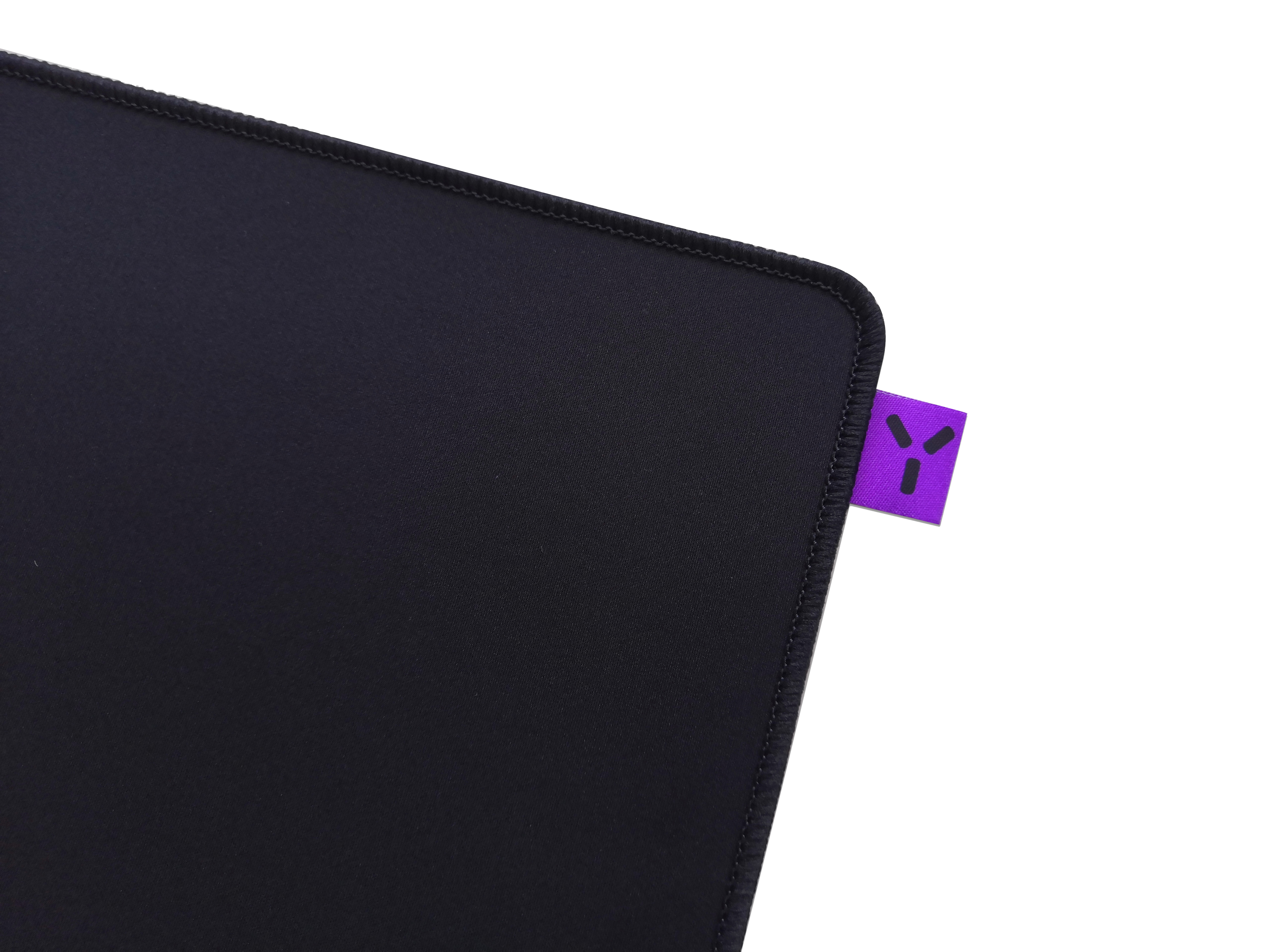 Ein schwarzes Mousepad mit einem lila Anhänger in der Ecke.