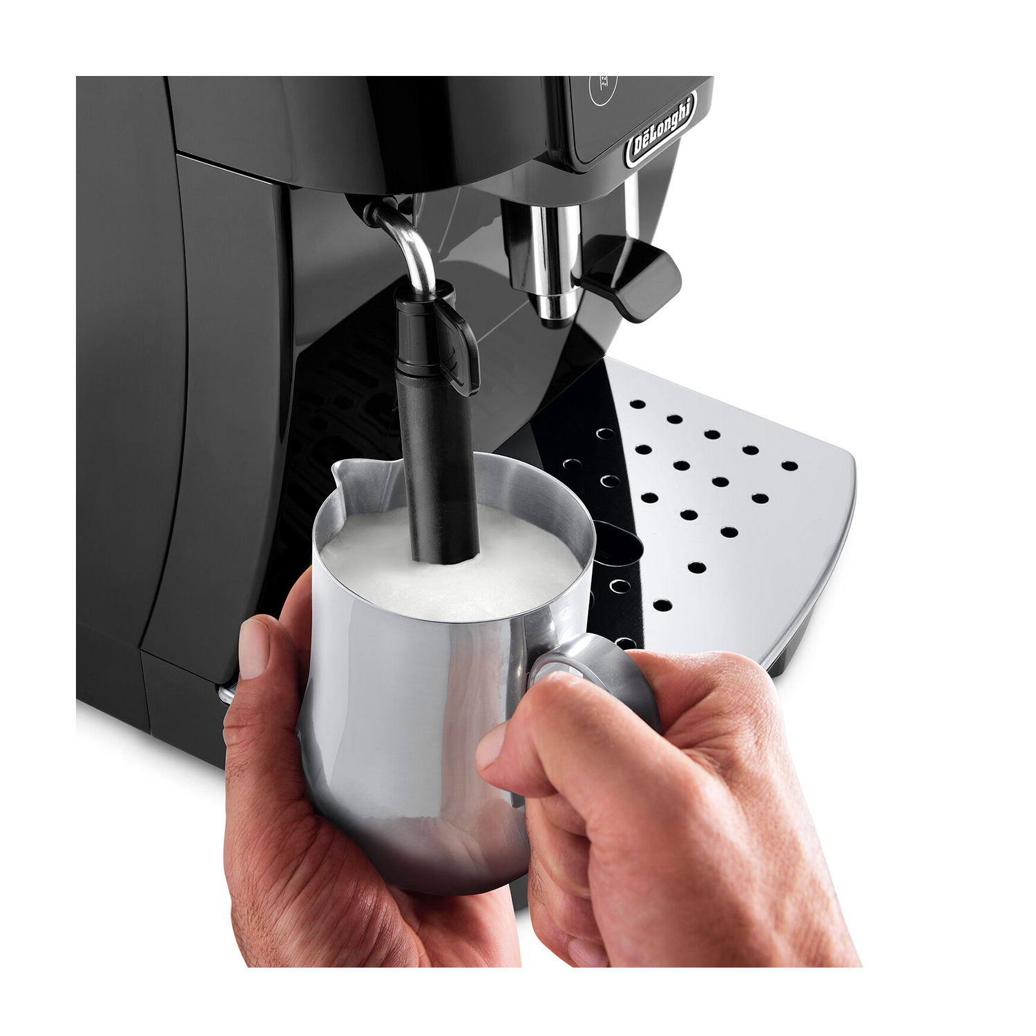 La mano di una persona che monta il latte con una macchina per espresso Delonghi. Viene utilizzato un bricco d'argento.
