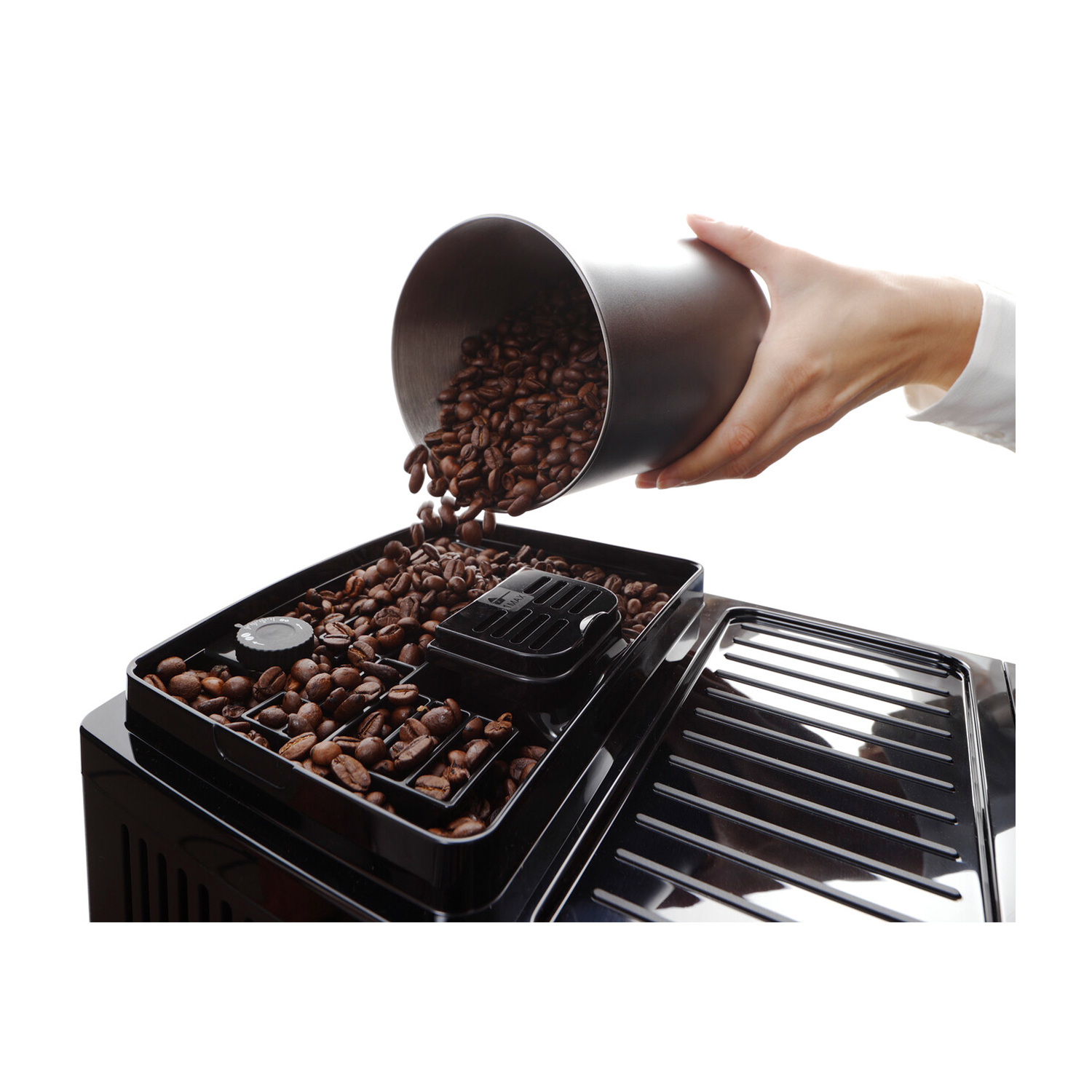 Mano che versa chicchi di caffè in un vassoio della macchina del caffè. Sfondo bianco.