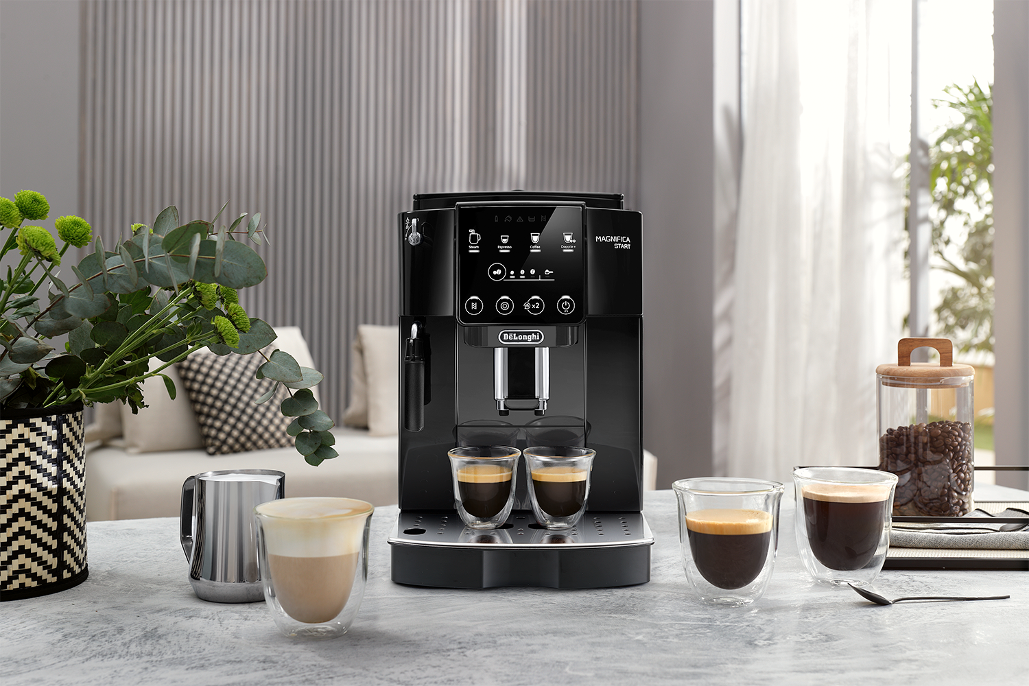 Black DeLonghi Magnifica Start coffee machine. Two coffee cups and a glass jar.