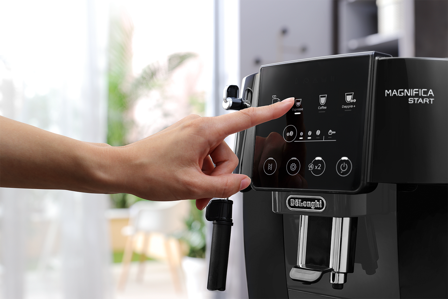Hand presses a coffee machine button. Black machine with digital display. Kitchen background.