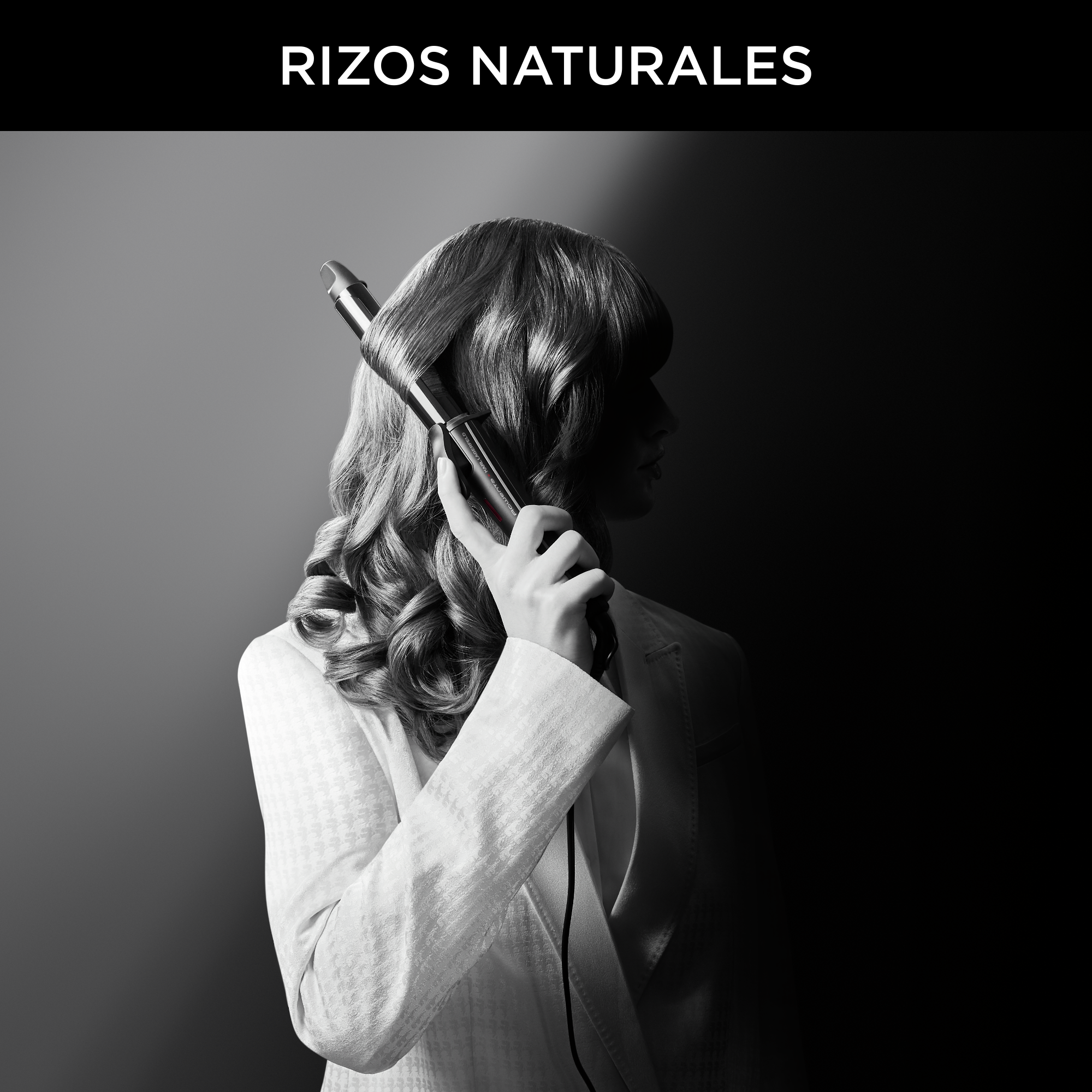 Mujer con rizador se riza el pelo, en foto blanco y negro.