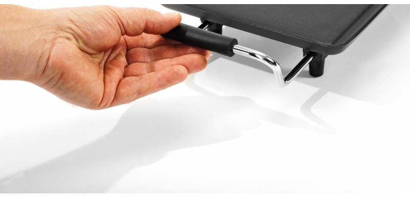 A hand holding a black grill pan handle, casting a shadow on a white surface.