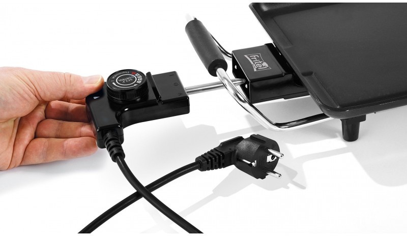 A hand holding a black electric grill control, with a plug and grill visible.