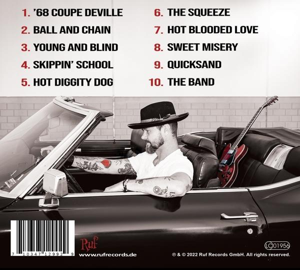 Mann in einem Cabrio mit Gitarrenkoffer. Die Titelliste des Albums ist sichtbar.