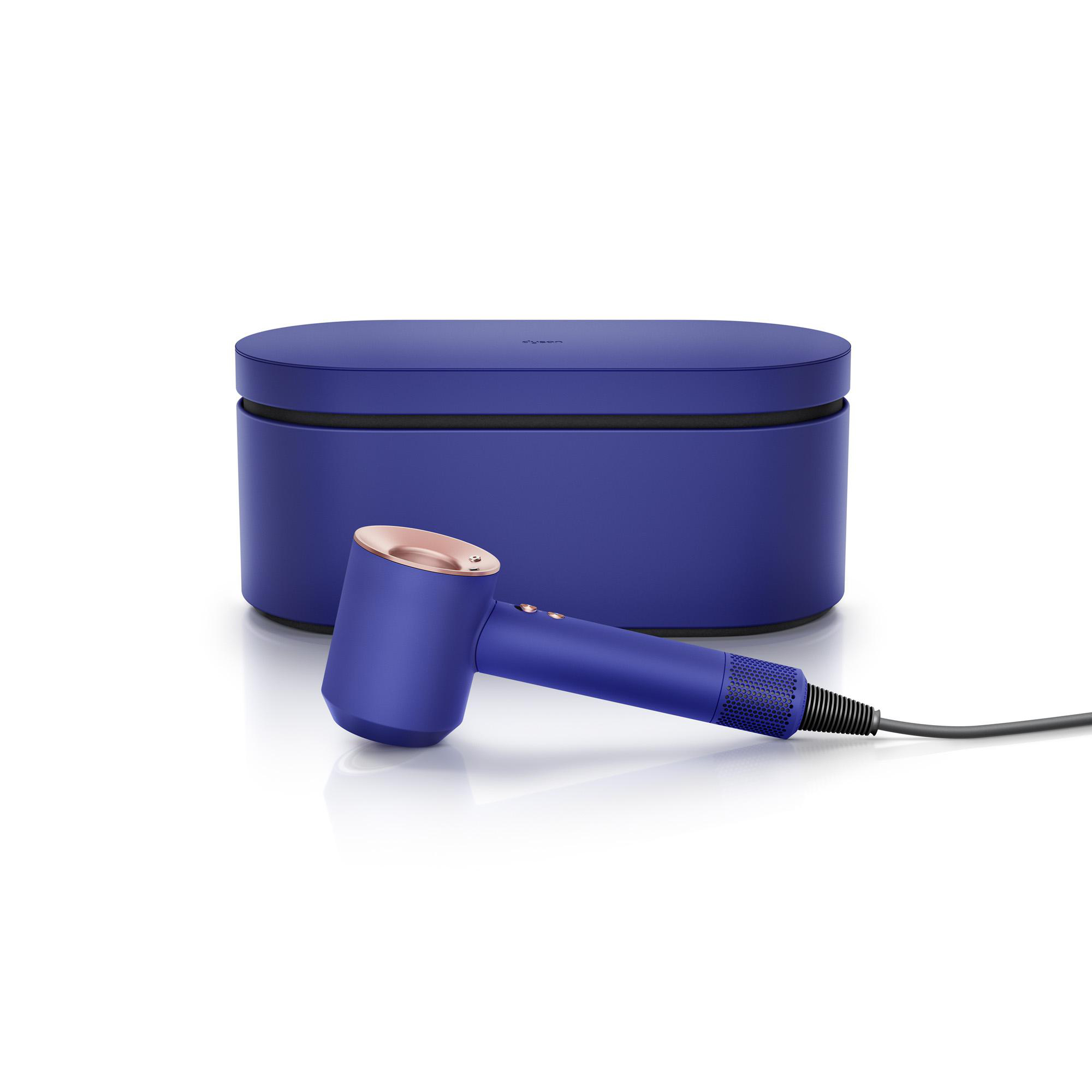 Ein blauer Dyson-Haartrockner und seine blaue Hülle liegen auf einer weißen Oberfläche.