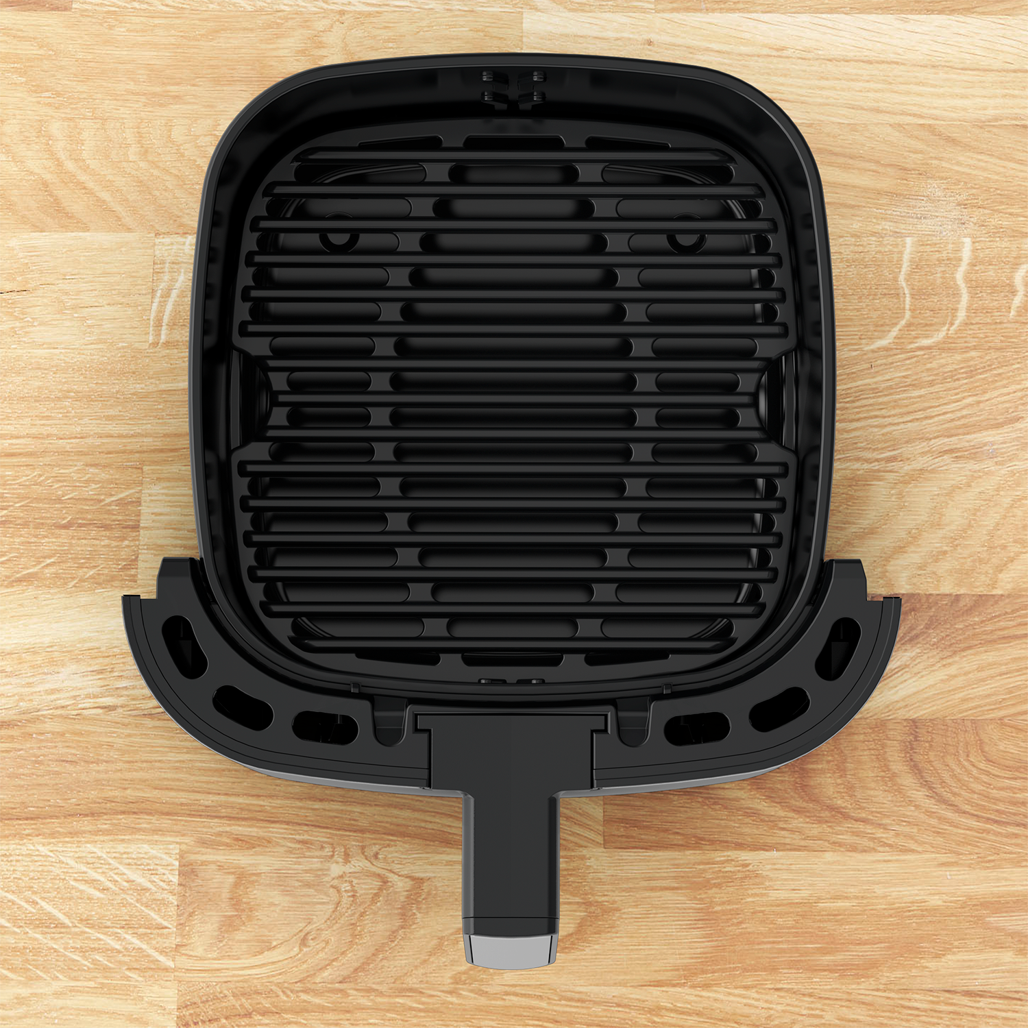 Black air fryer basket with grid design on a wooden surface.