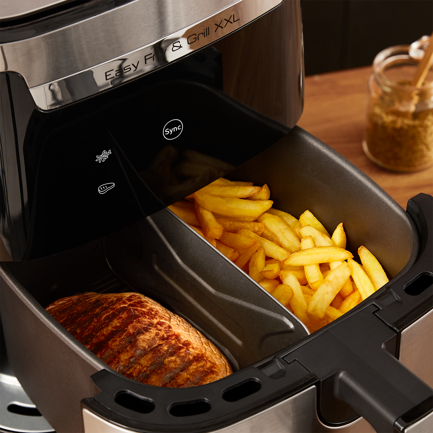 An air fryer with cooked steak and fries. The air fryer is open.