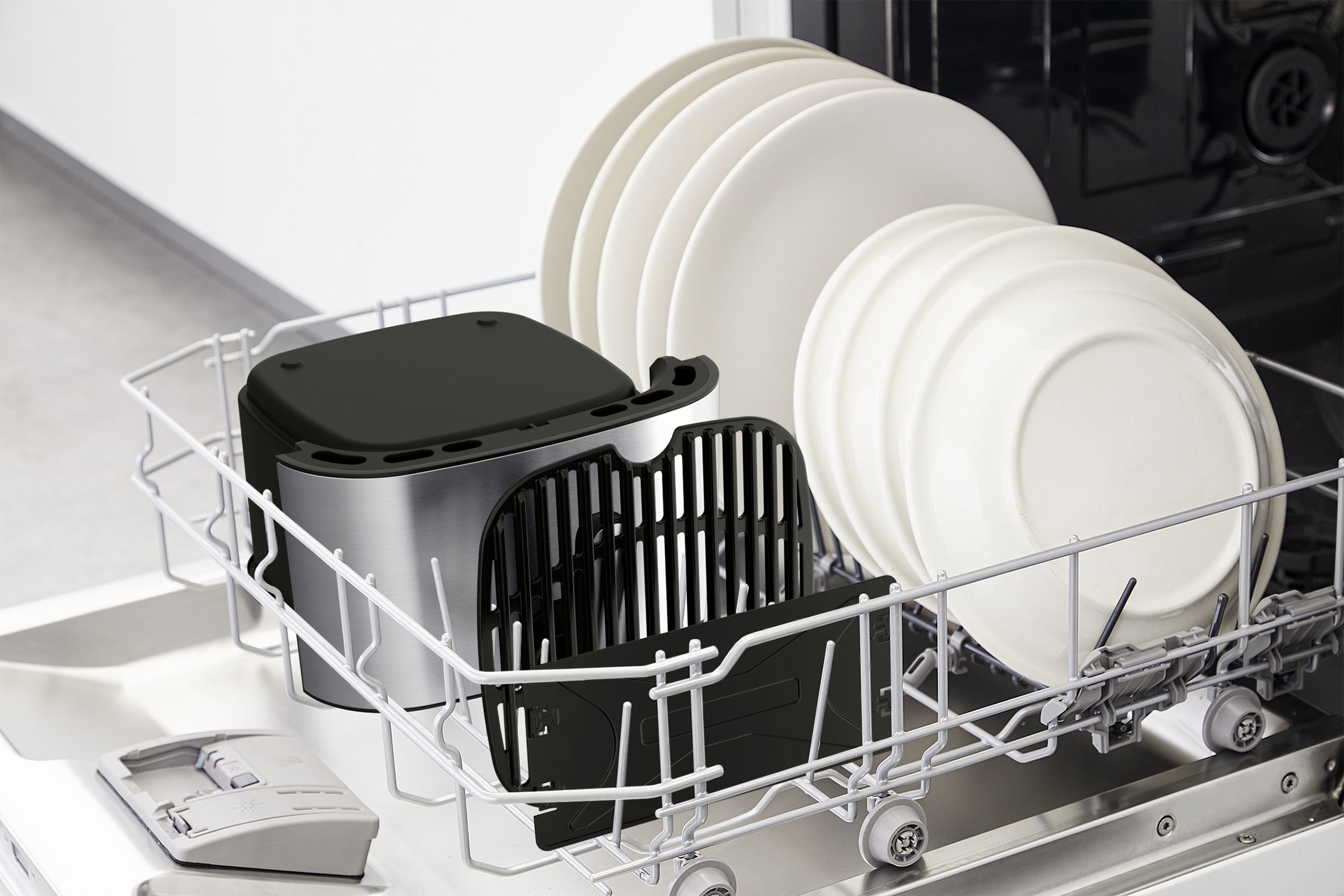 Dishwasher with a rack of plates, a black air fryer basket, and other accessories.