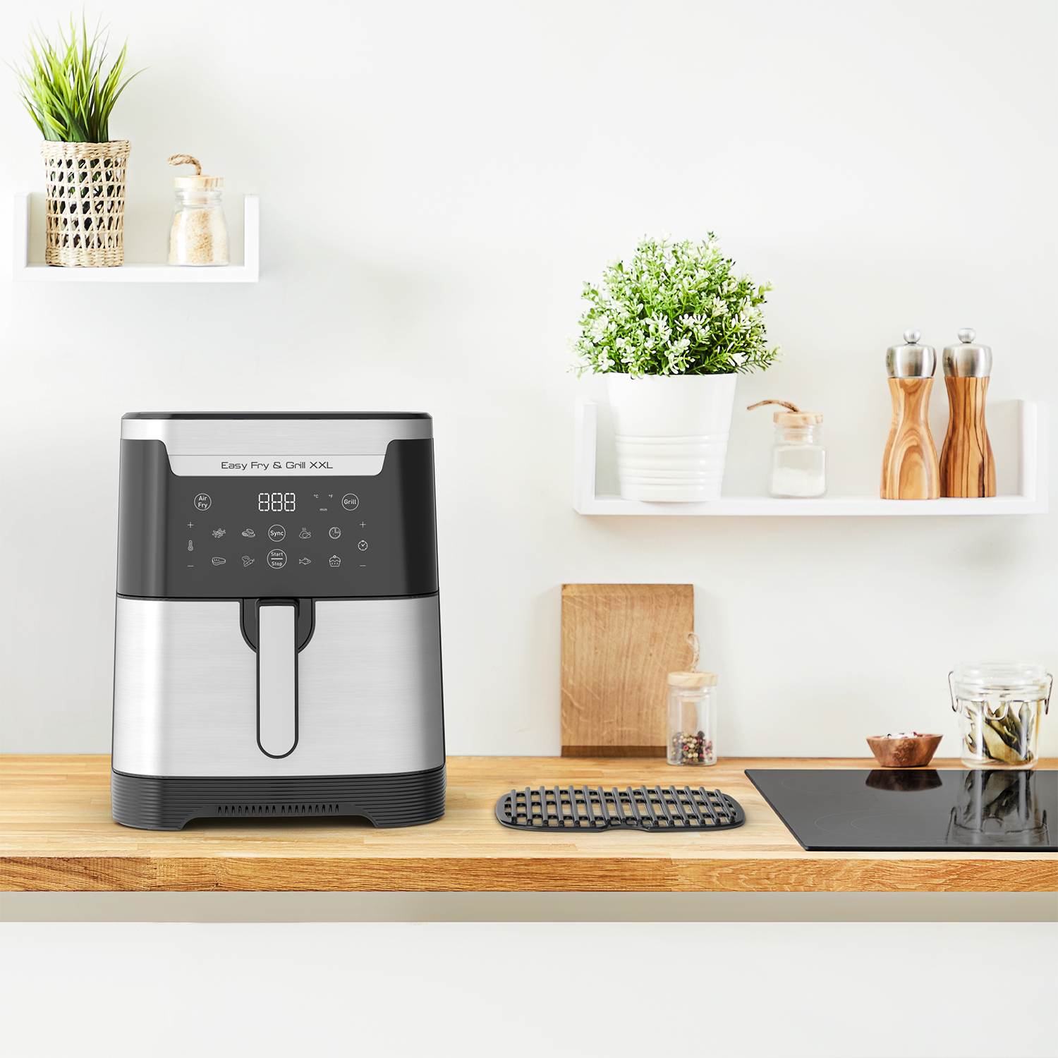 Air fryer on a wooden counter. White shelves hold plants and spices.