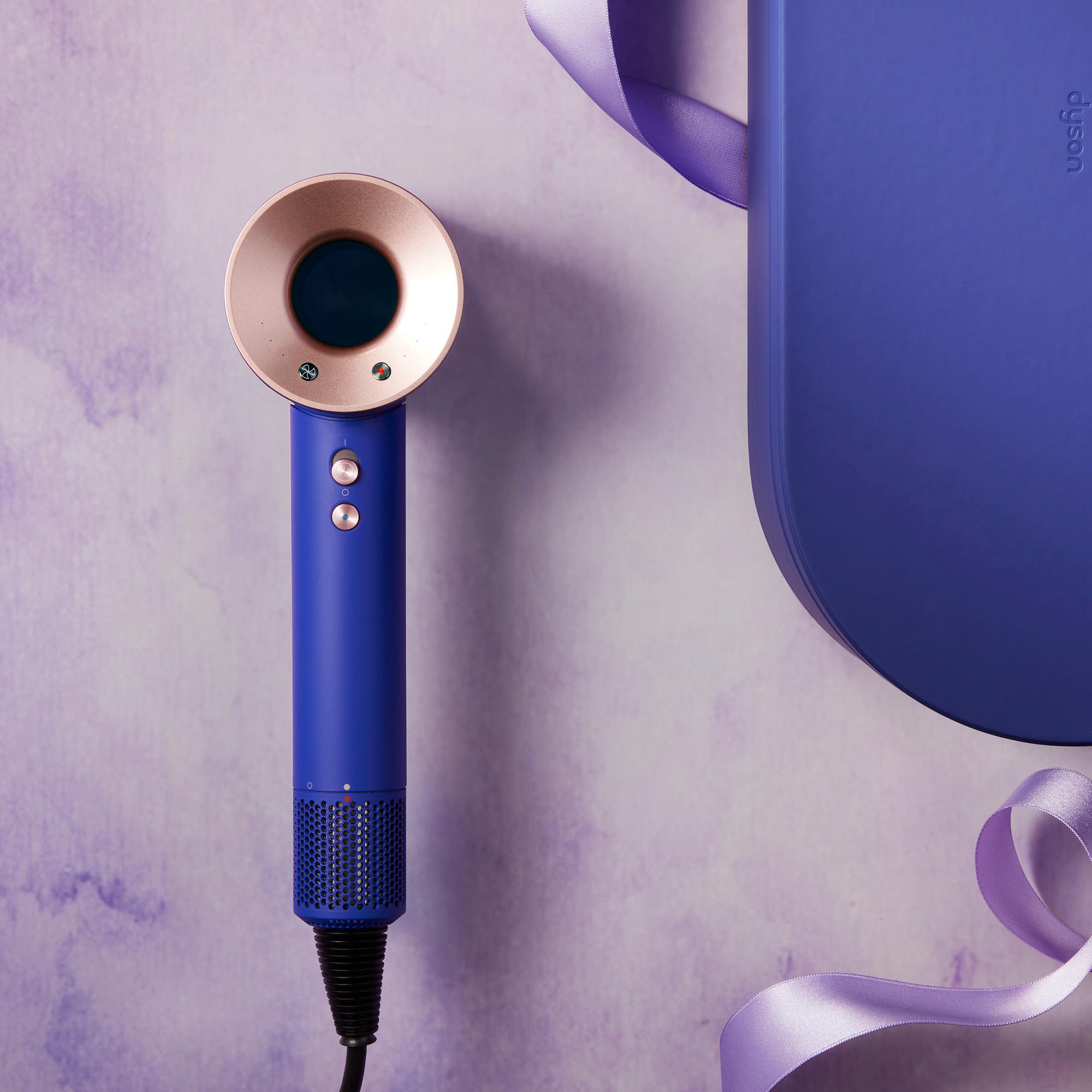 Ein blauer Dyson Haartrockner. Ein Etui und ein Band sind auch im Bild.