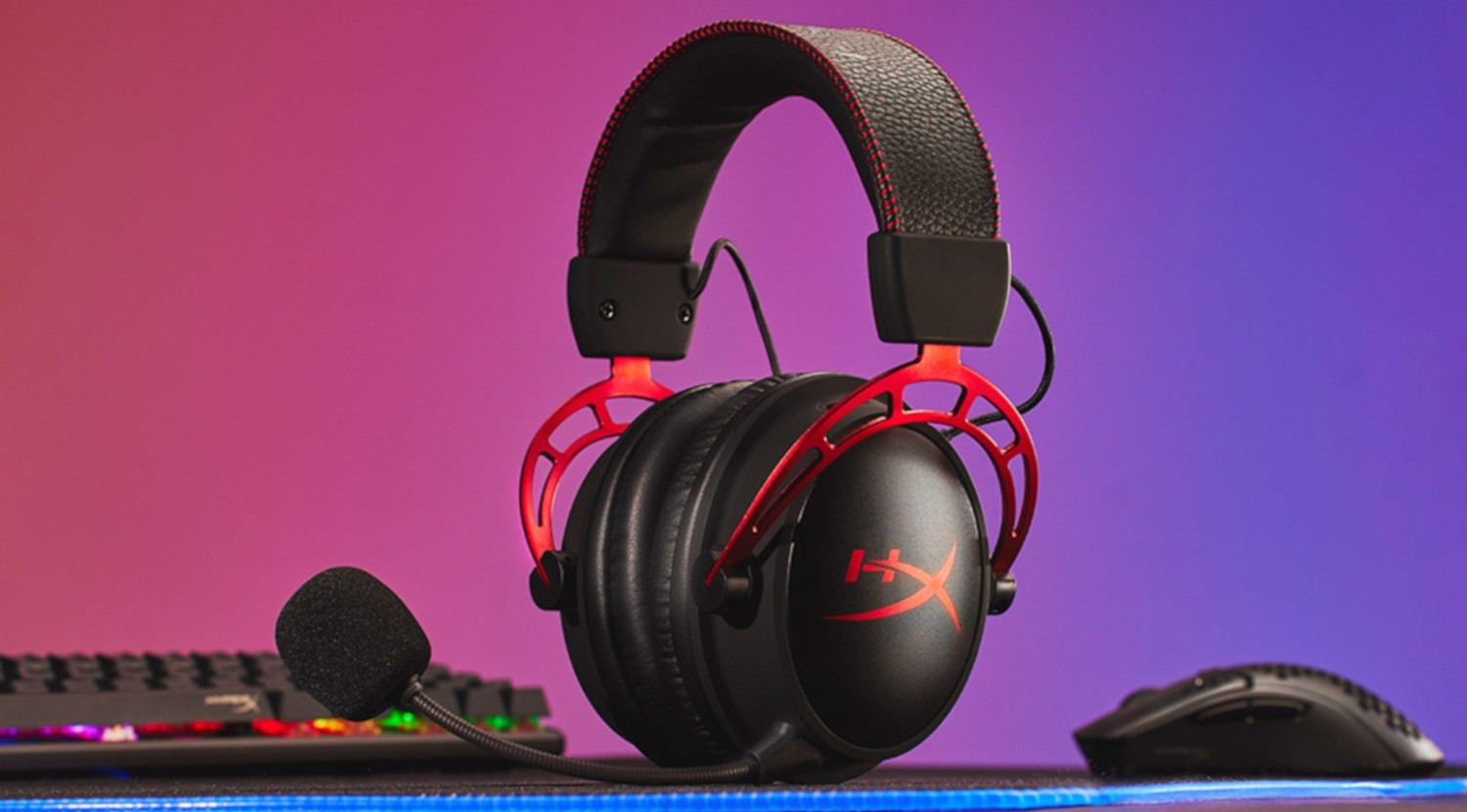 Black and red gaming headset with a microphone, next to a keyboard and mouse.