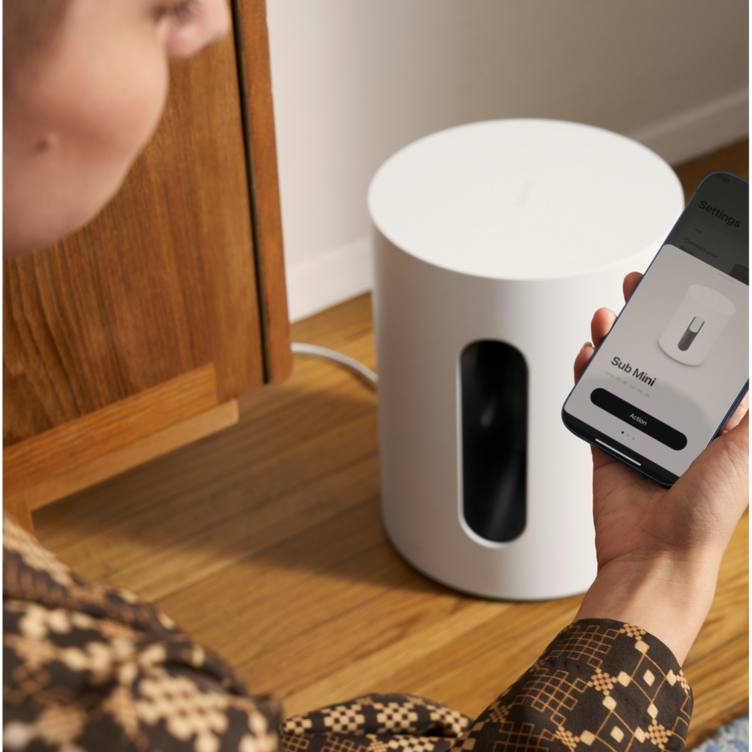 Una persona conecta un teléfono a un altavoz Sonos blanco. El teléfono muestra la configuración.