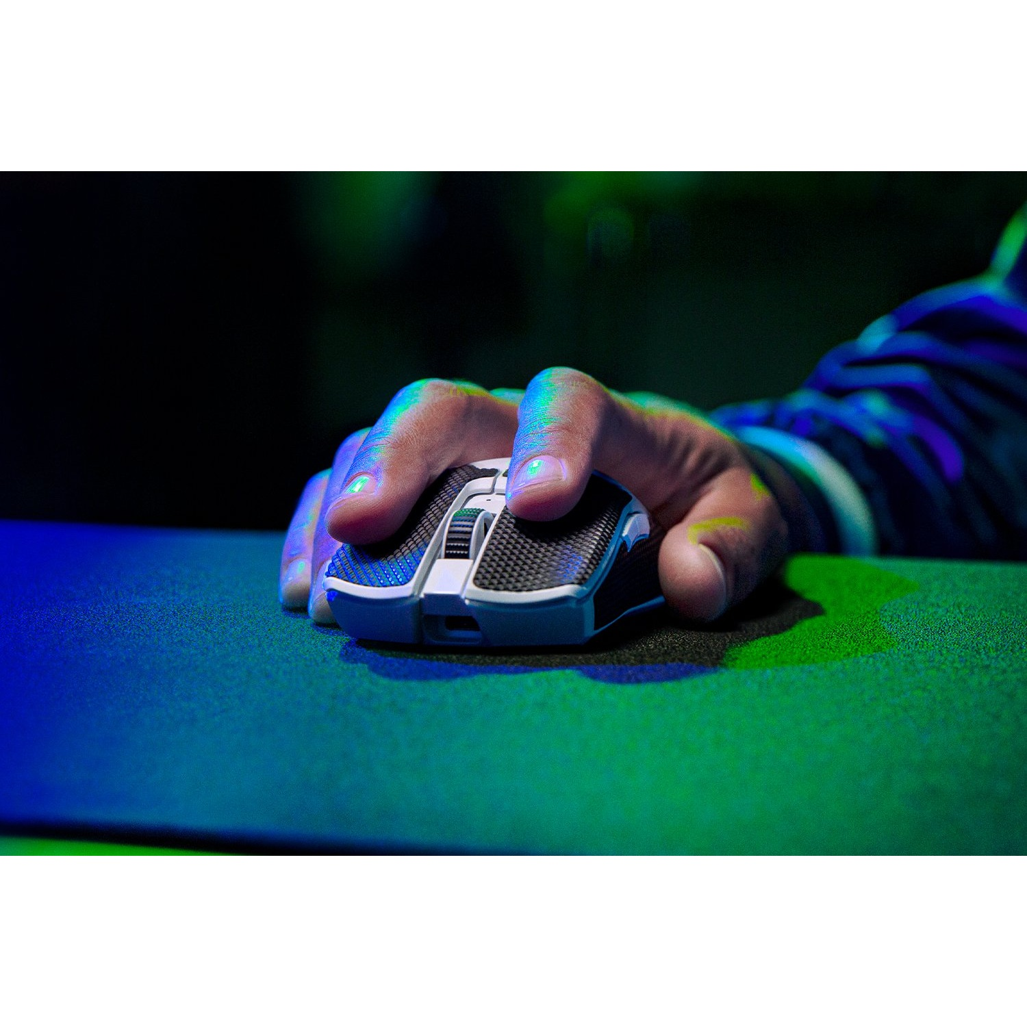 La mano de una persona usando un ratón gaming sobre una alfombrilla verde y azul.