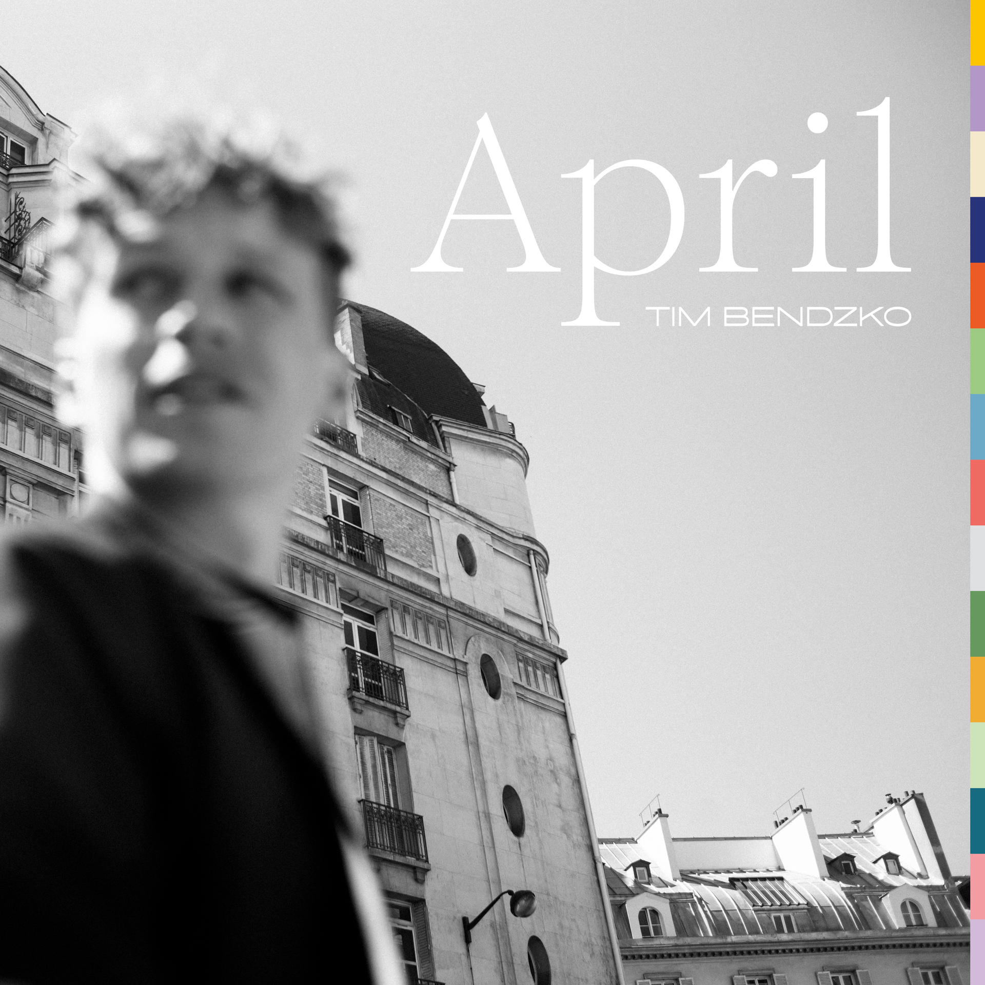 Schwarz-Weiß-Foto eines Mannes vor Gebäuden mit dem Wort 'April'.