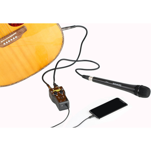 Bir gitar, bir mikrofon, siyah bir akıllı telefon ve bağlı küçük bir ses cihazı.
